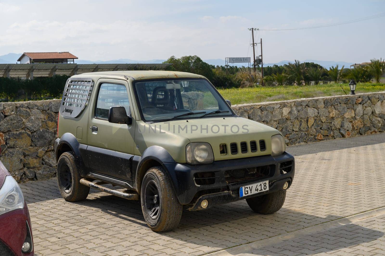 Gaziveren Cyprus -15.02.2025 A rugged vehicle sits in a quiet area amidst greenery and stone walls, reflecting a harmonious countryside vibe.