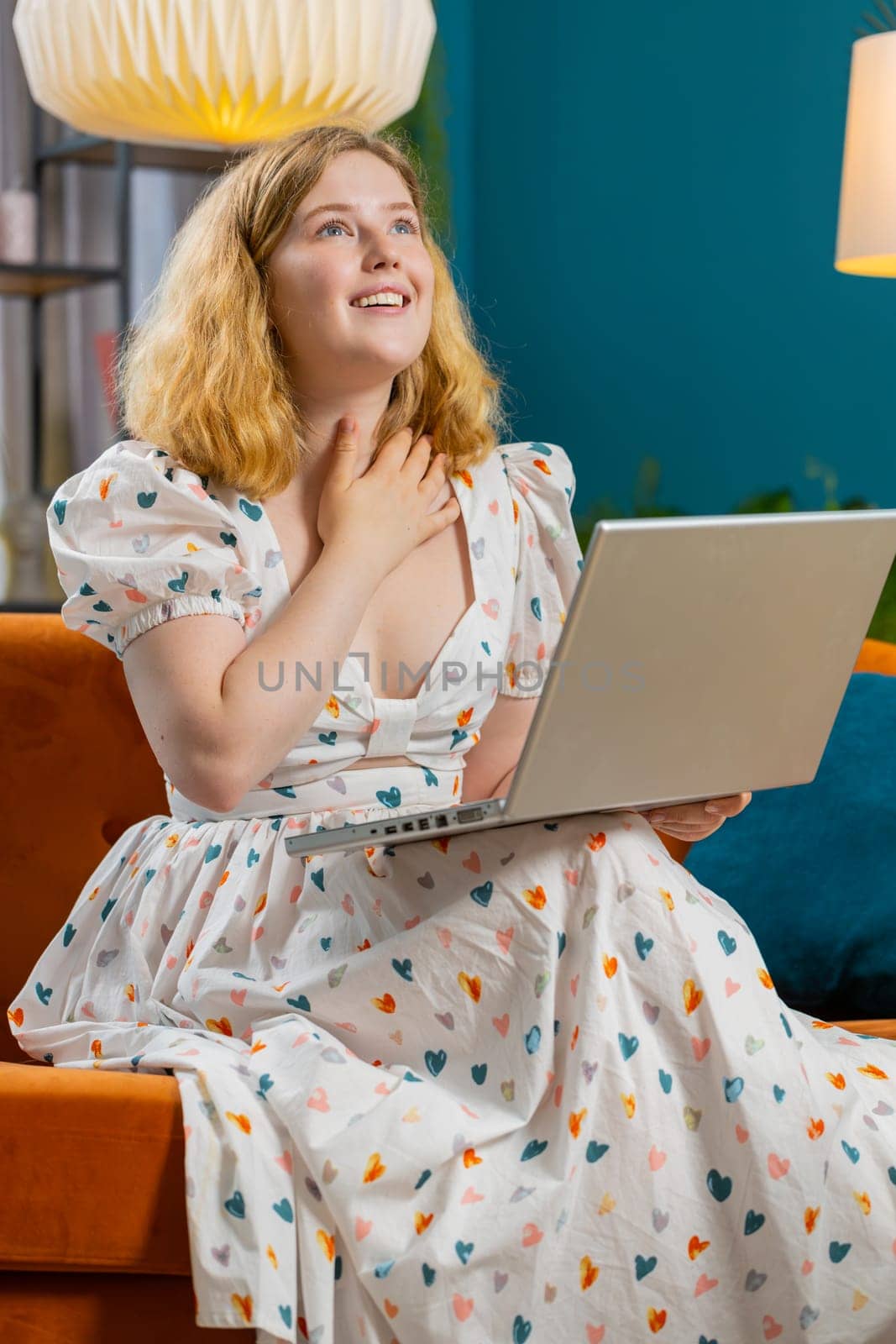 Surprised happy redhead young adult woman using laptop computer receive good news success message shocked by sudden victory celebrate lottery jackpot win purchases online shopping at home. Vertical