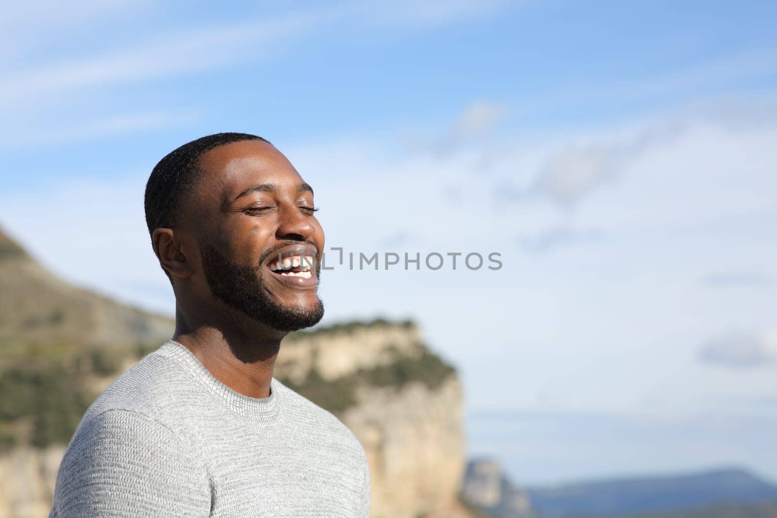 Funny man with black skin laughing outdoors with copy space
