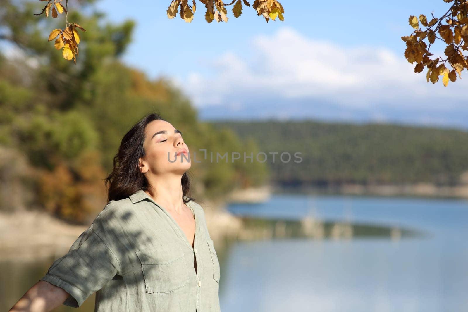 Woman breathing fresh air relaxing in a lake in autumn