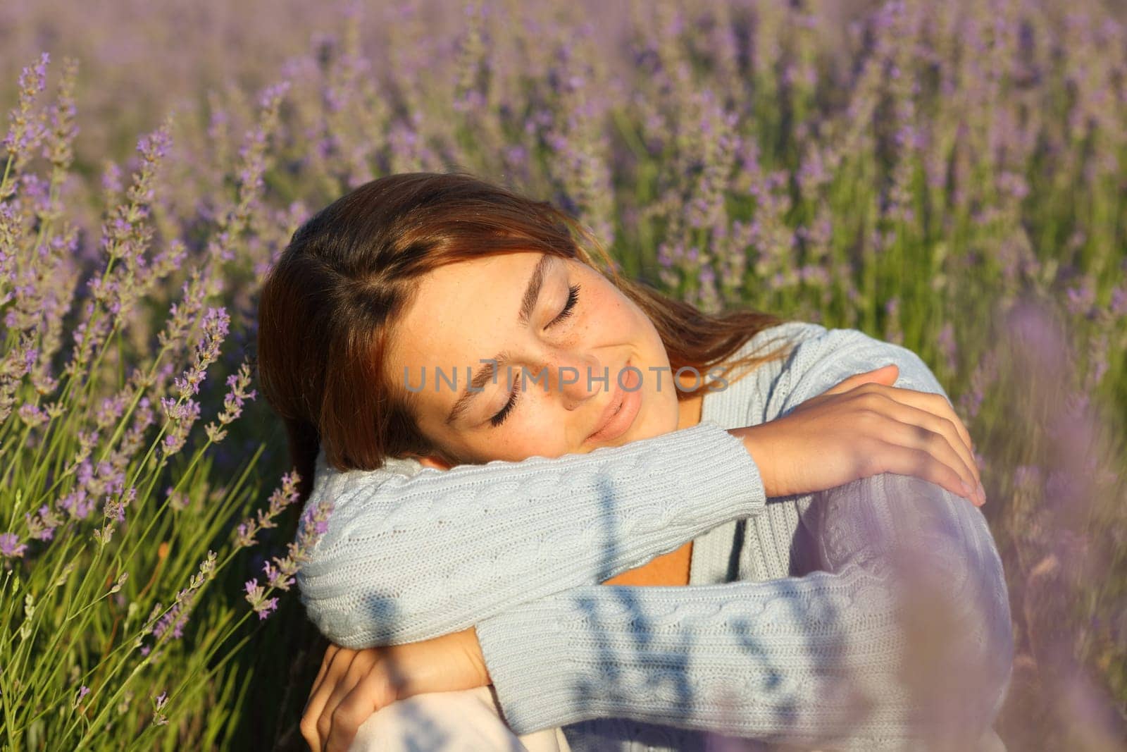 Happy woman relaxing with closed eyes sitting in lavender field
