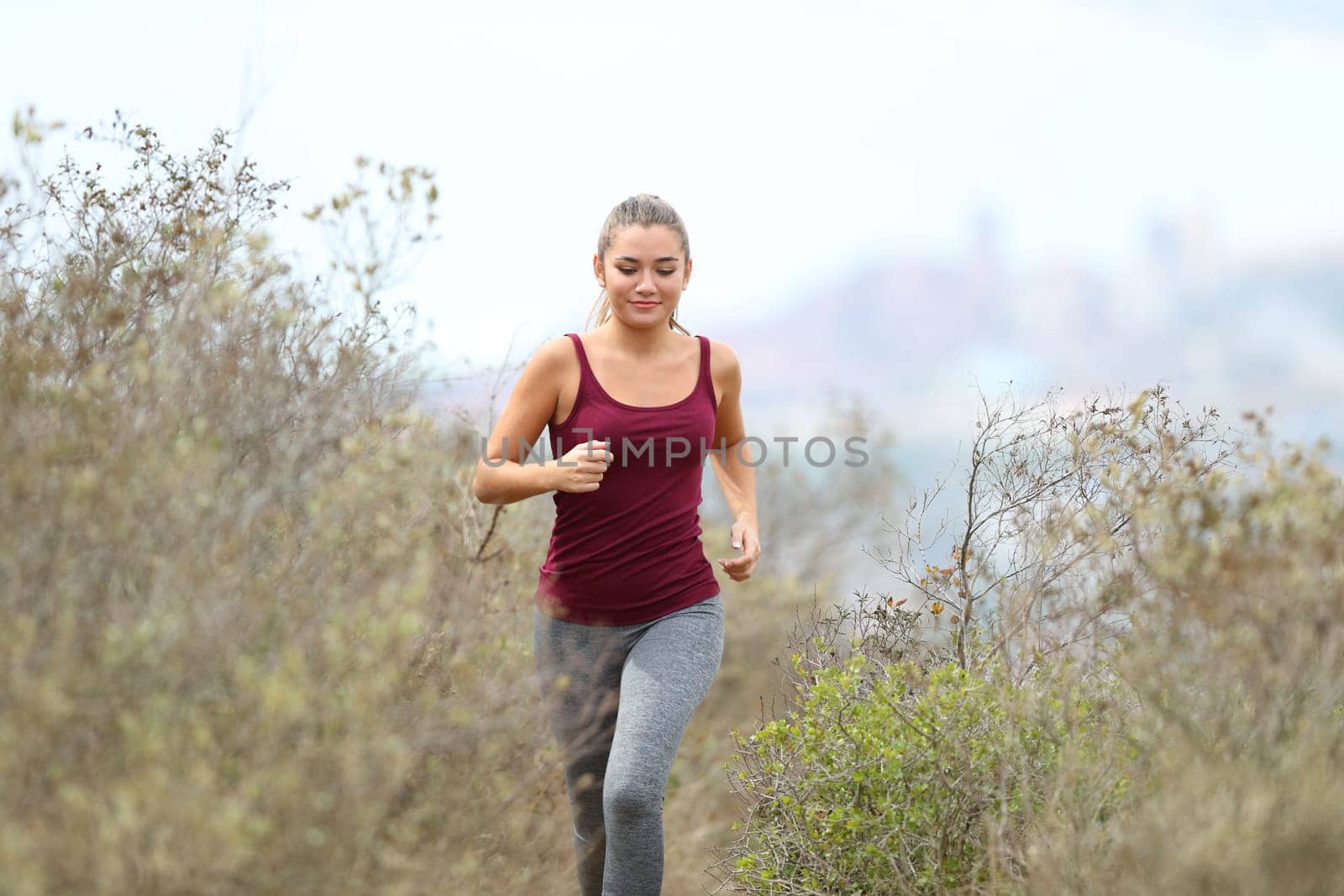 Front view portrait of a runner running towards camera in the mountain