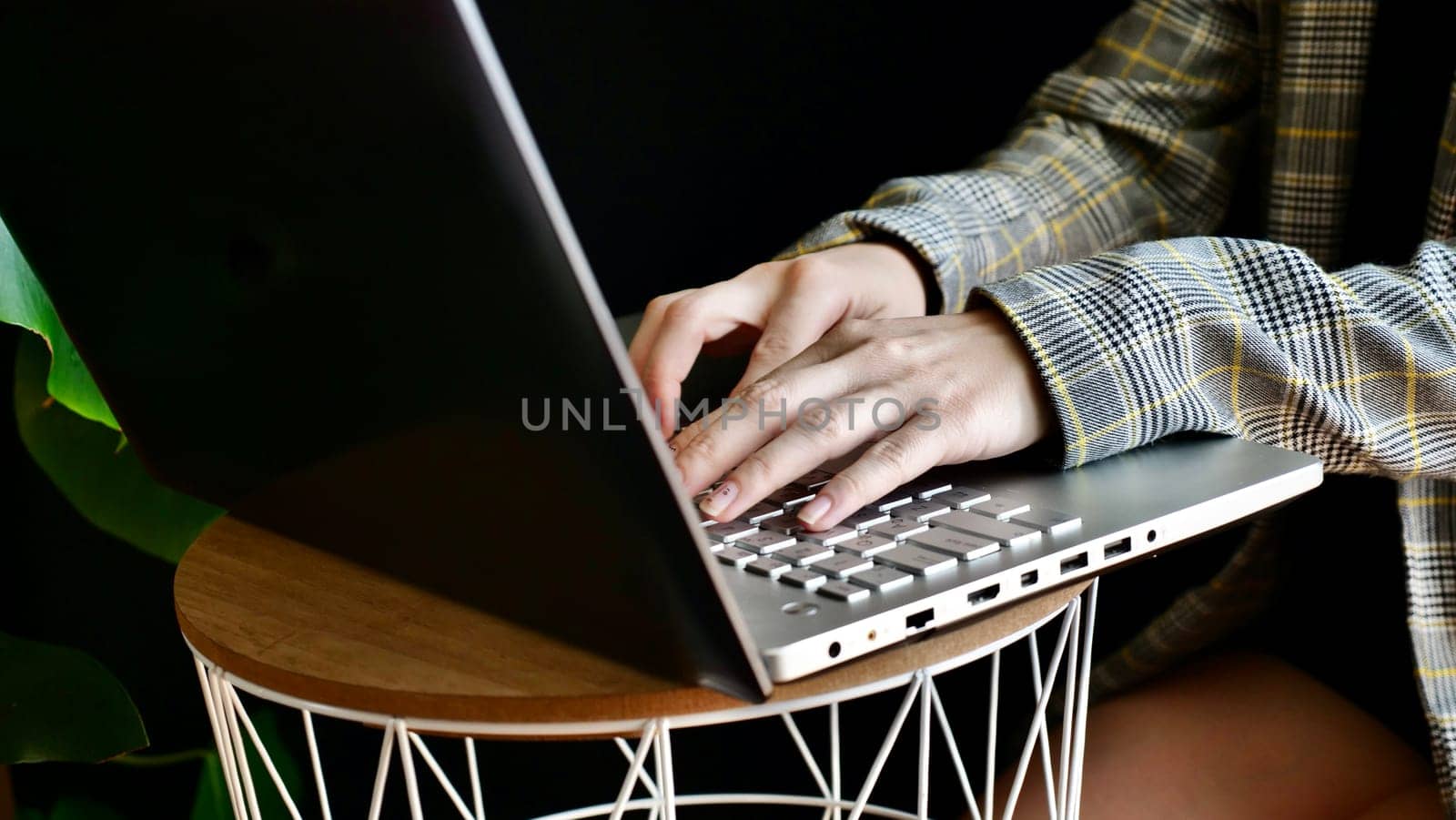 Close-up of woman's hands in a jacket typing on a laptop computer. The person works, studies at home online. No face.