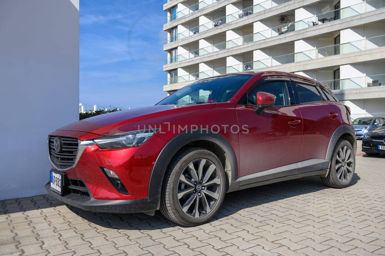 Gaziveren Cyprus -15.02.2025 A striking red crossover vehicle is parked against a backdrop of sleek modern buildings under bright sunlight.