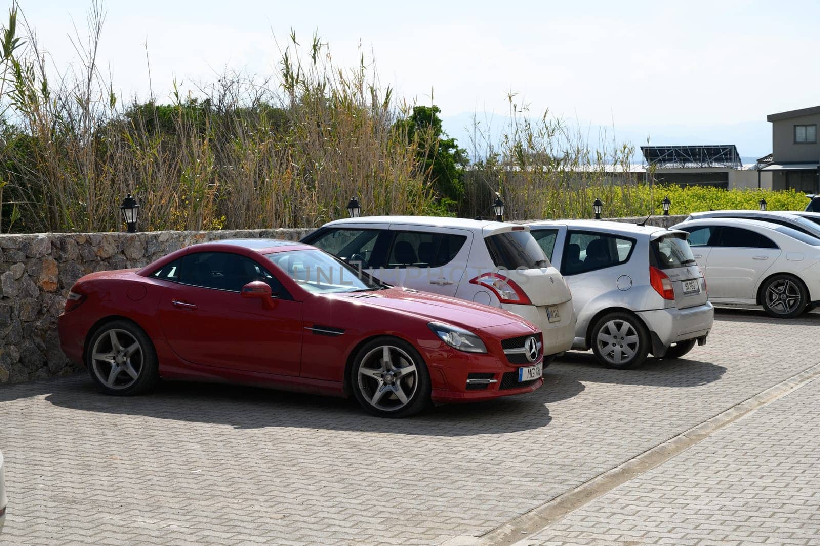 Gaziveren Cyprus -15.02.2025 A striking red sports car is nestled between smaller cars, basking in the warm sunlight of a beautiful day.