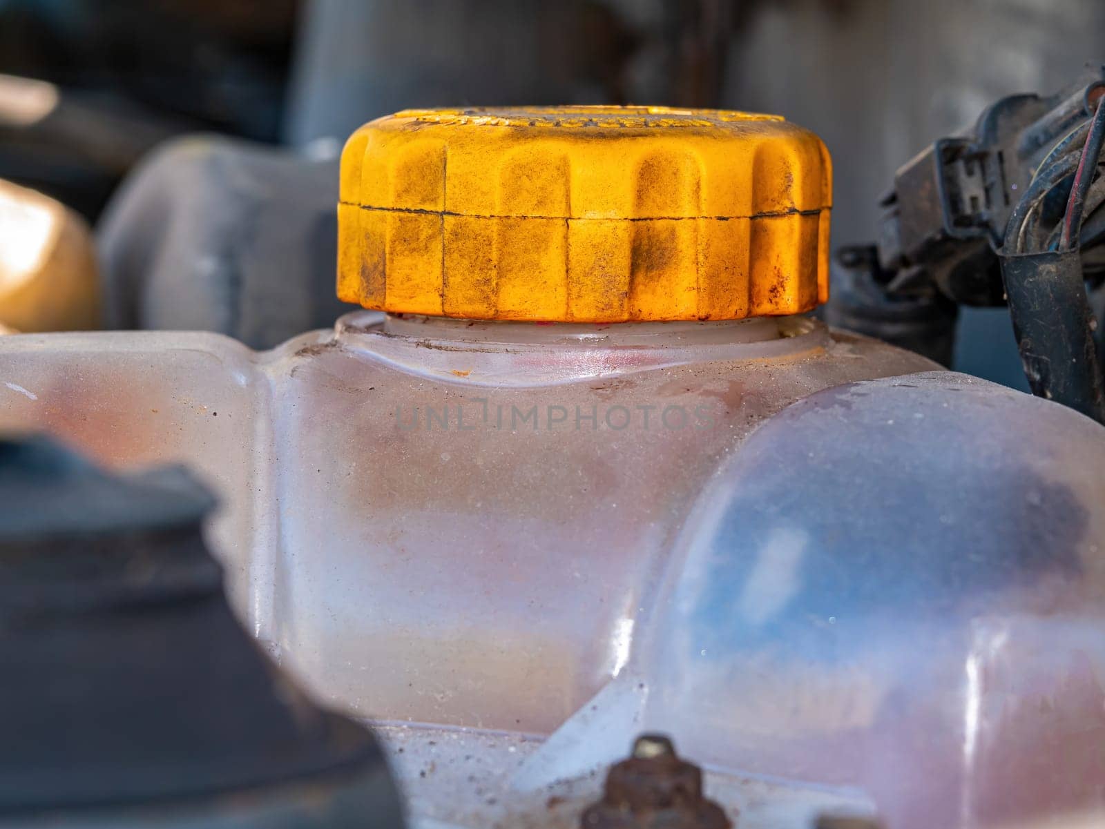 Plastic tank with a yellow cap for antifreeze of the car engine cooling system. Plastic tank with yellow lid. Liquid container. Refueling antifreeze. Car repair. Customer Service. Coolant.