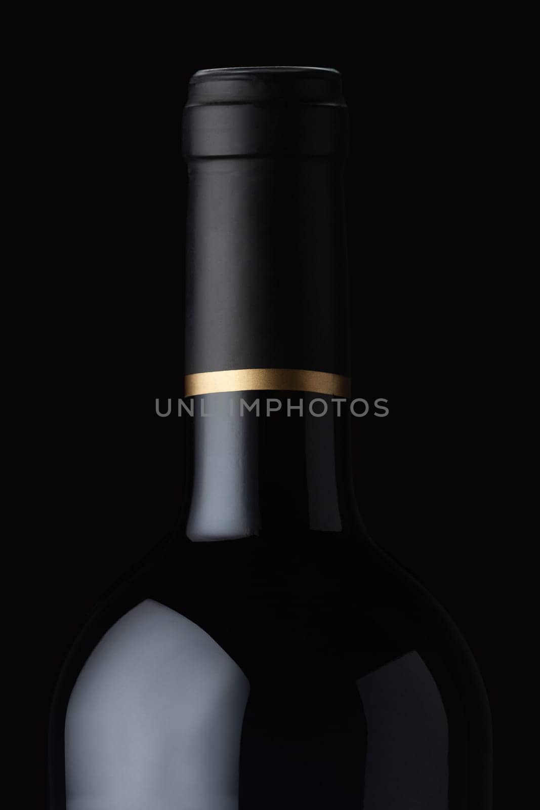 front view close up of expensive black red wine bottle with golden cap stripe on dark background with glass reflections