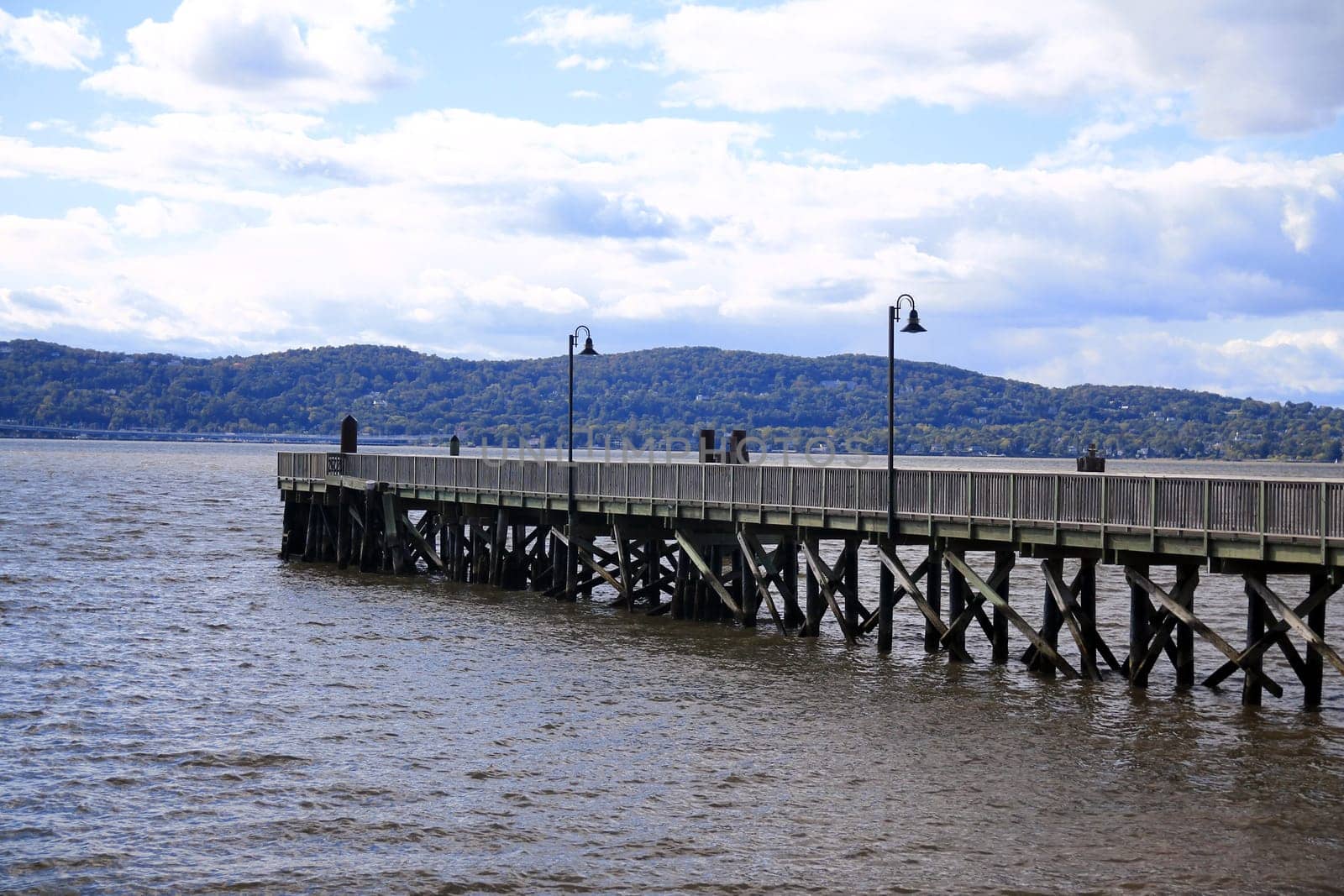 The wooden pier with the black lamps on the brown Hudson river