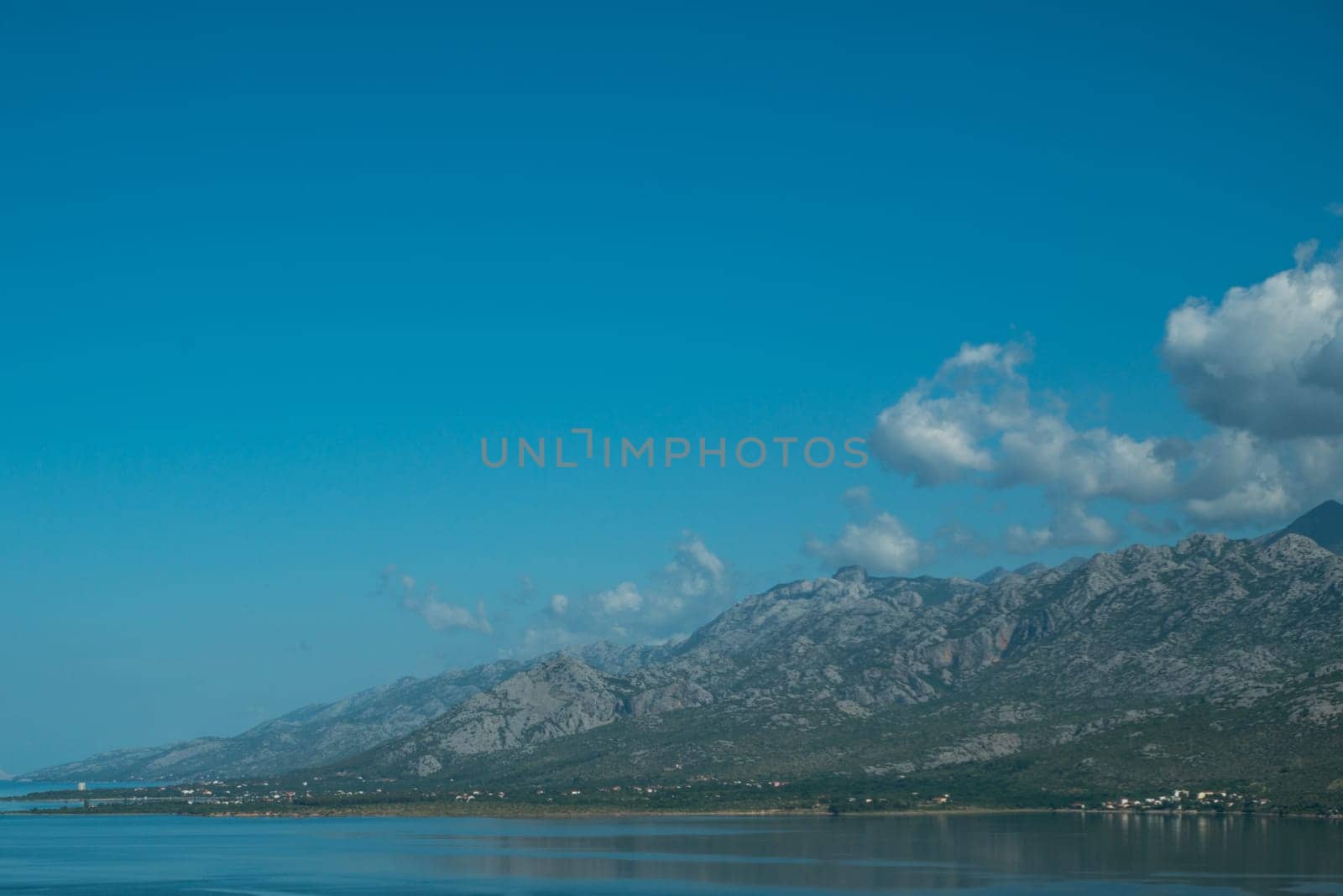 Beautiful coast, blue sea and mountains in the distance. Nice view of the blue Adriatic sea during a sunny day.