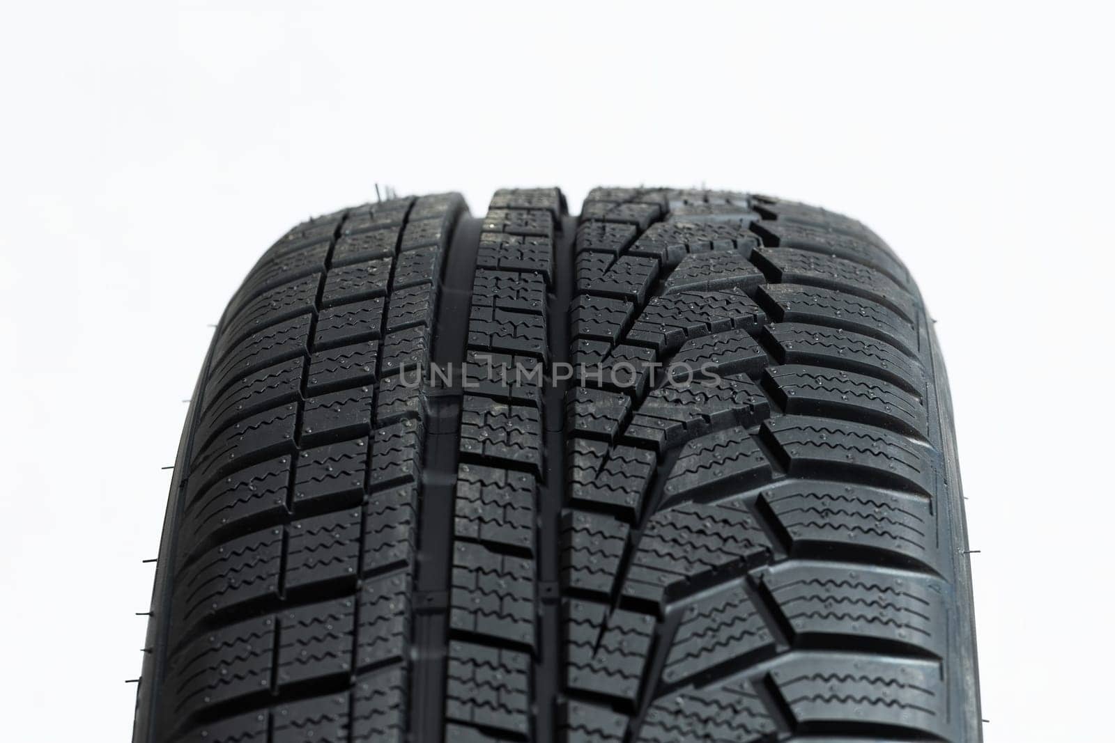 Detailed close-up view of winter tire isolated on white background. Regular pattern on rubber wheels cut out on blank. Concept of traction on roads in wintertime.
