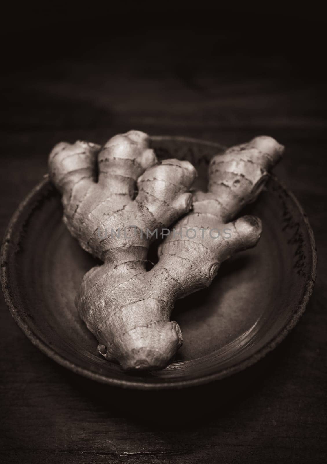 Ginger in handmade clay bowl on wooden table