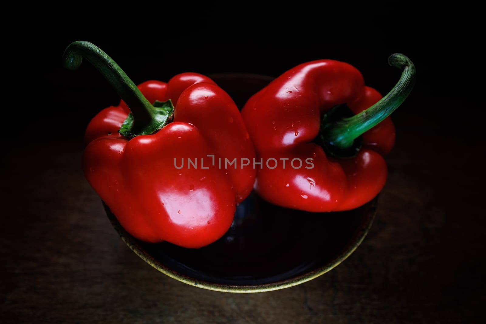 Two red pepper in bowl dark backround