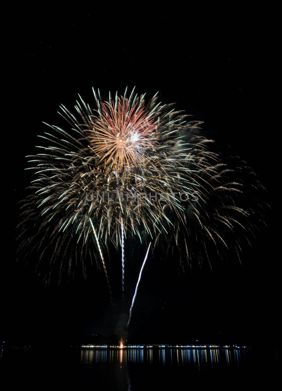 Colorful fireworks exploding with reflection on lake