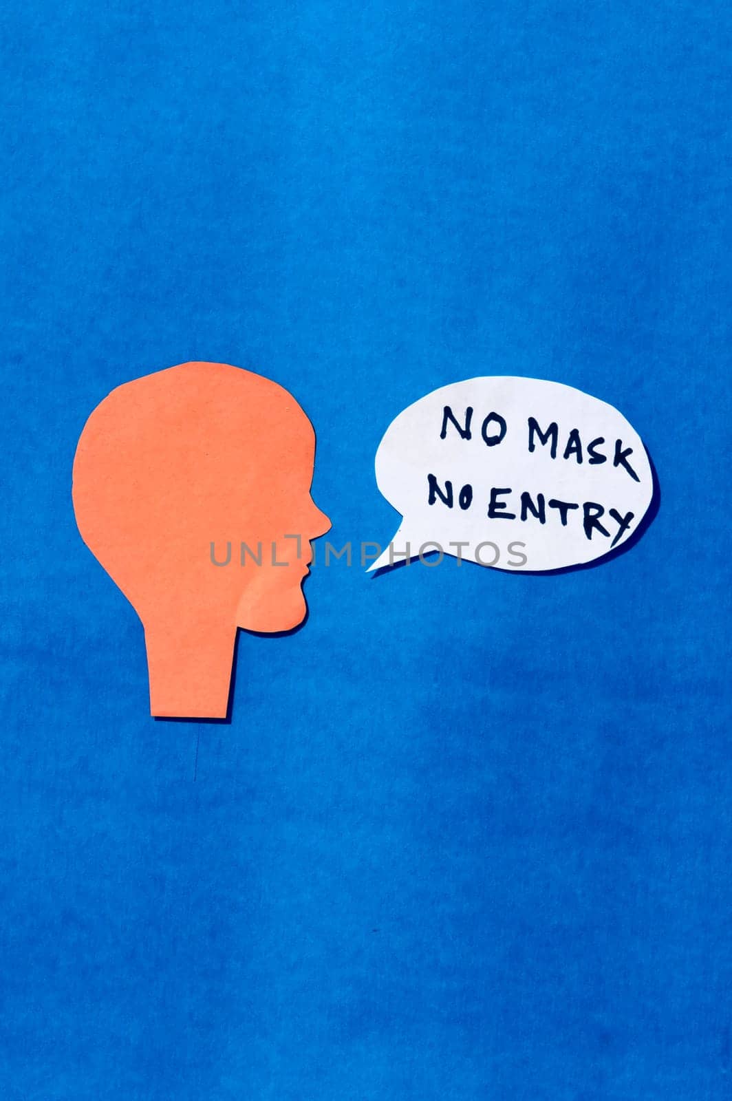 Paper Human face with No Mask No Entry sign on speech bubble isolated on blue background. Conceptual images showing that a person must accepts the conditions of wearing a mask before entering.