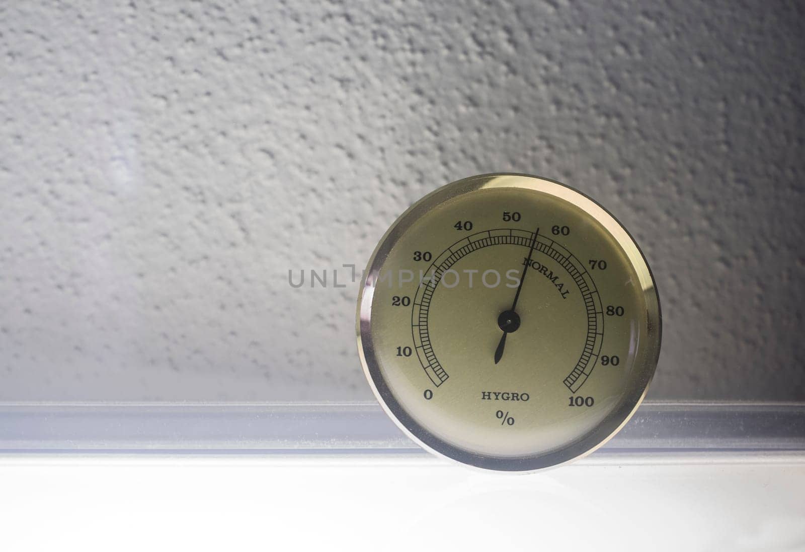 Analog hygrometer attached to glass museum cabinet. Selective focus