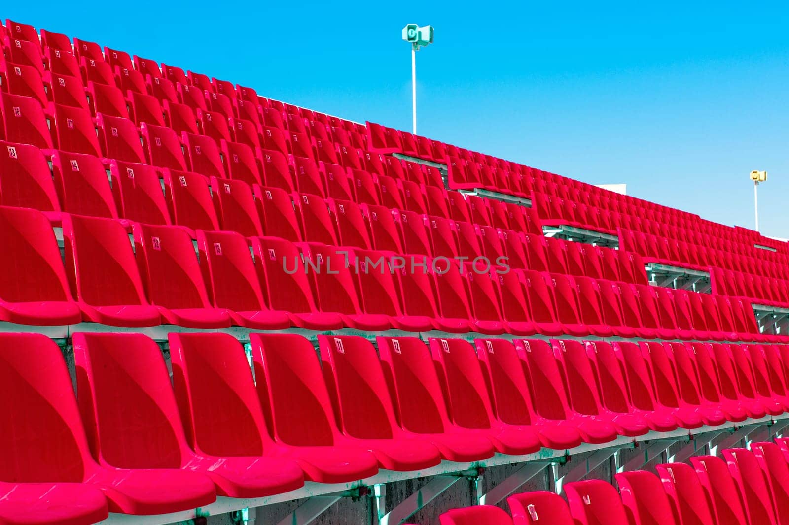 The Rows of empty red color plastic stadium seating on the terrace.