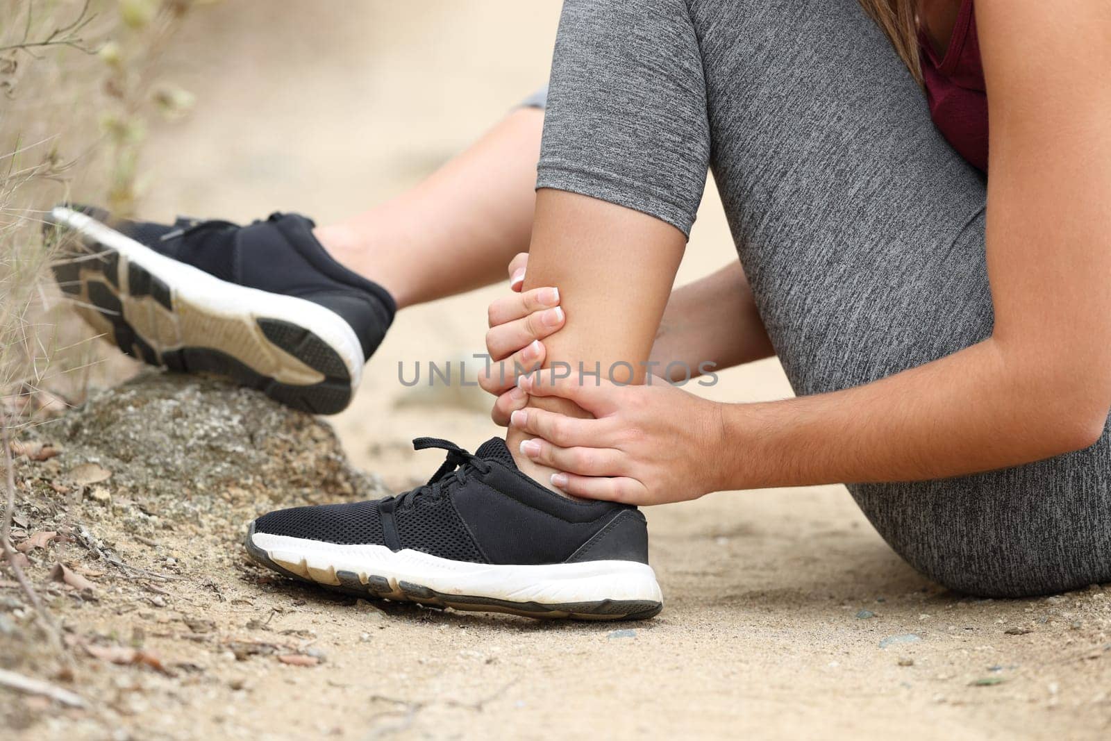 Close up of a runner hands grabbing sprained ankle in the mountain