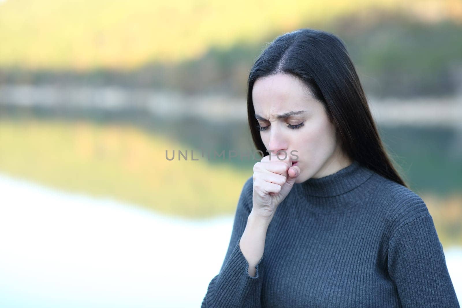 Woman coughing covering with hand in nature in winter