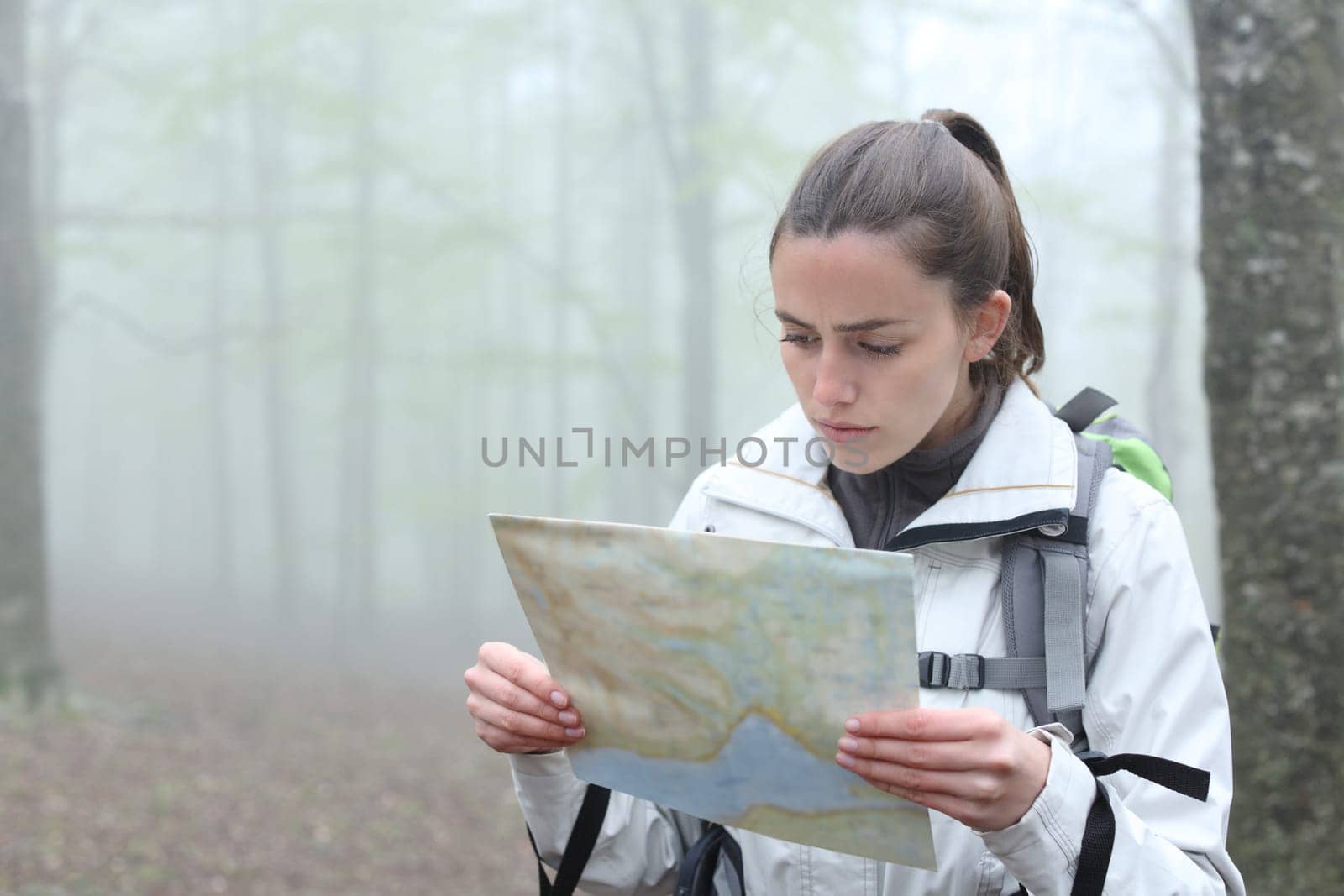 Serious trekker checking paper map to find location in a forest
