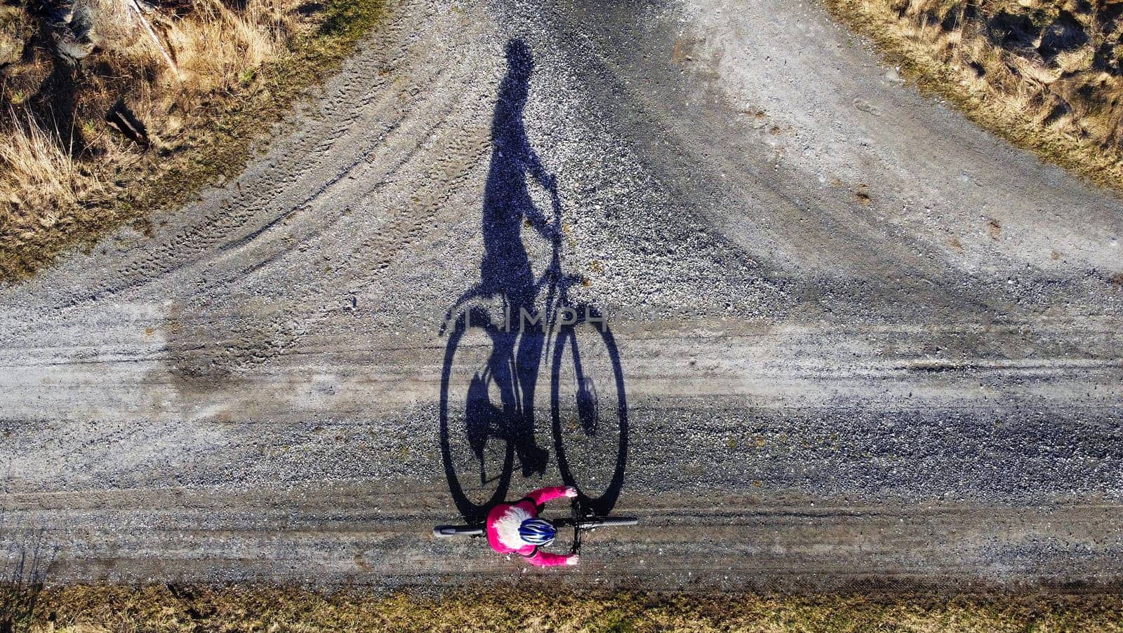 Aerial shot with drone of female cyclist on road with shadow