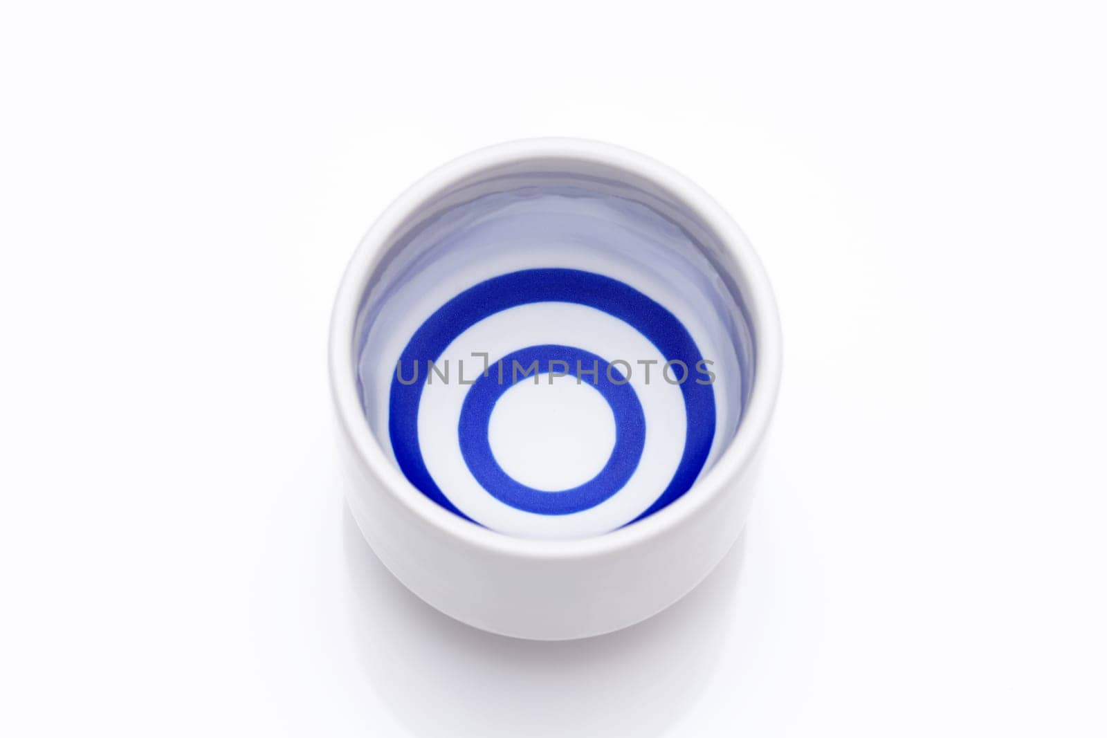 Japanese sake in a traditional ceramic ochoko cup on white background