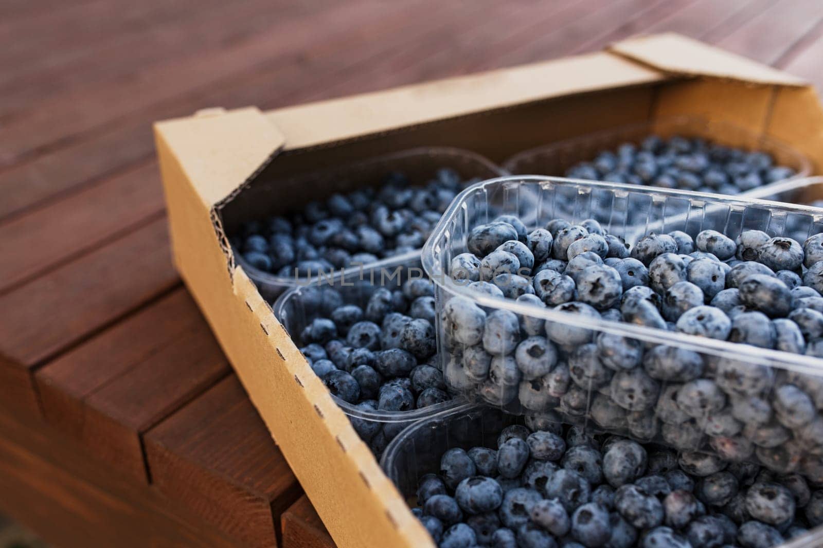 Box, crate or container with collected fresh blueberries. Berries agriculture business. Farmer cultivating and harvesting blueberry. Horticulture industry. Healthy eating. Wooden plank background