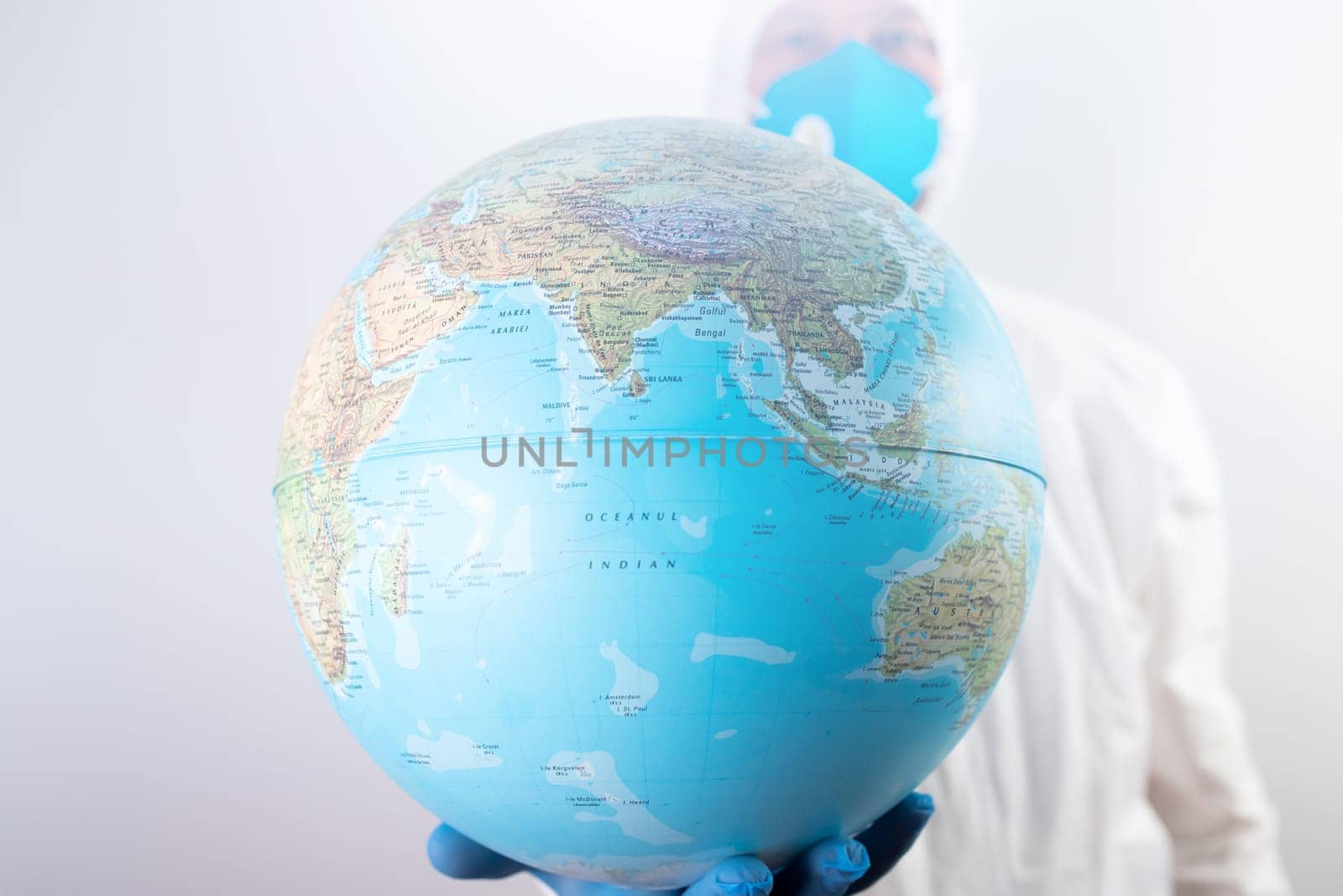 World epidemic danger concept. Male doctor man in medical face mask and gloves protecting planet Earth.