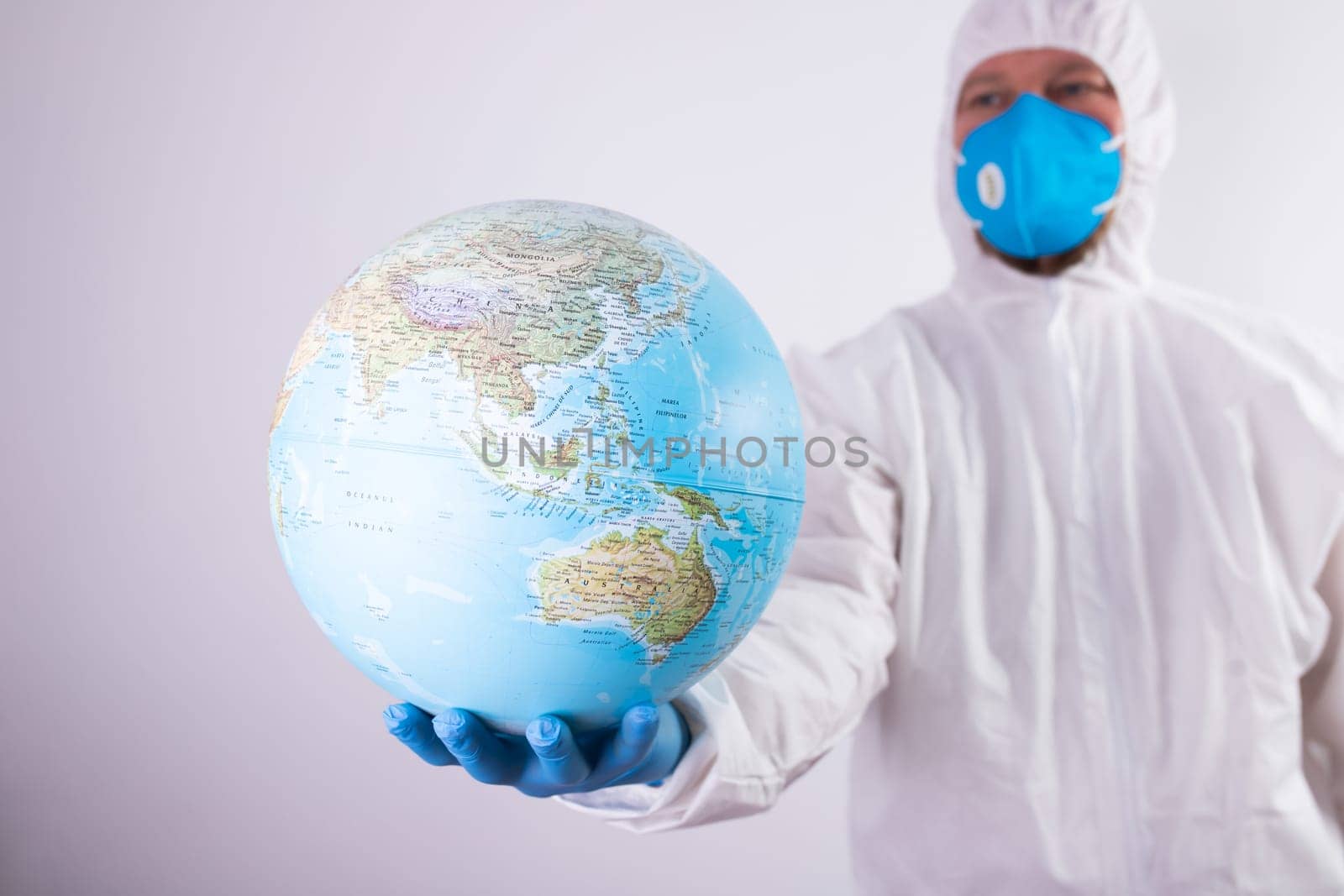World epidemic danger concept. Male doctor man in medical face mask and gloves protecting planet Earth.