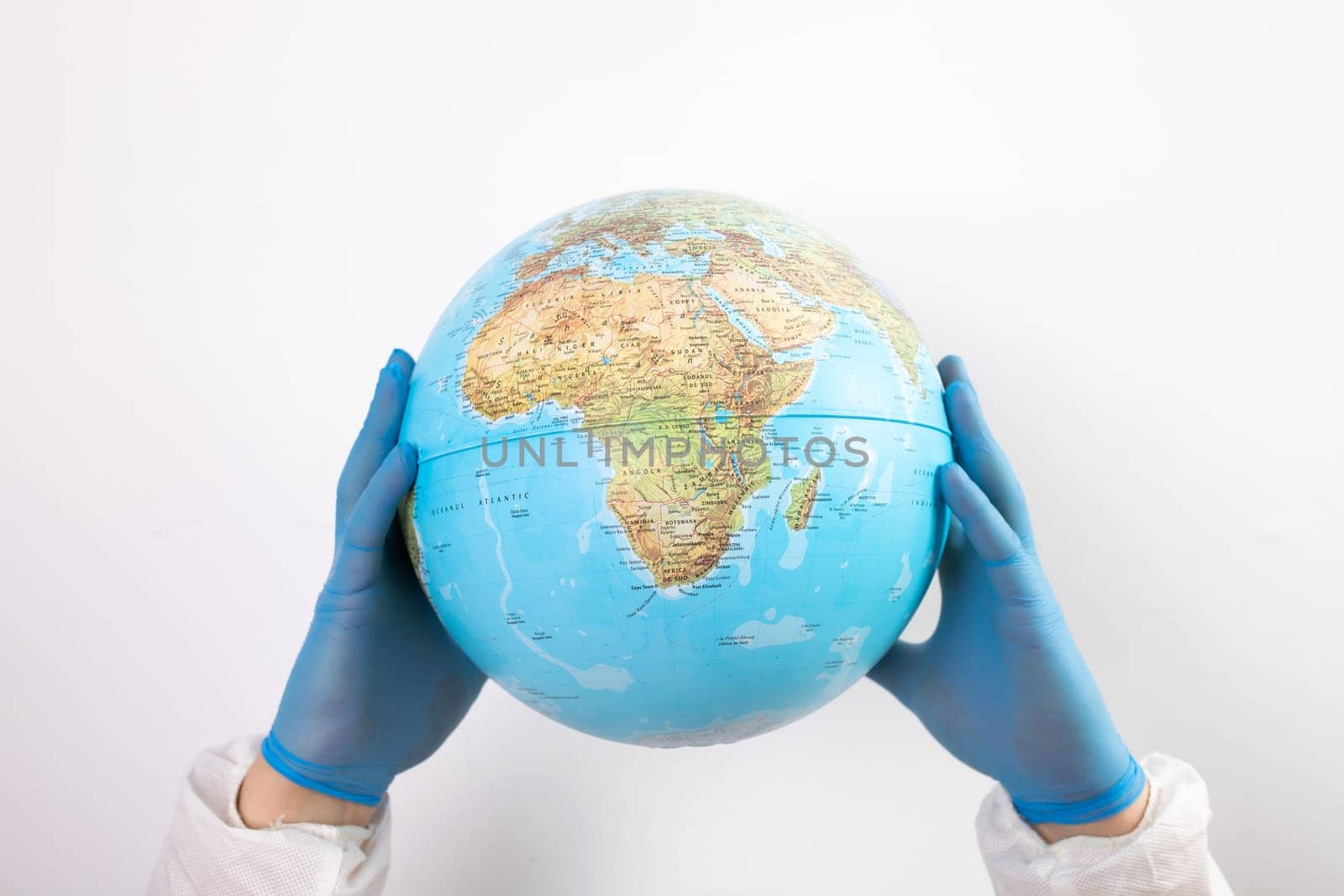 World epidemic danger concept. Hands of doctor in medical face mask and gloves protecting planet Earth.