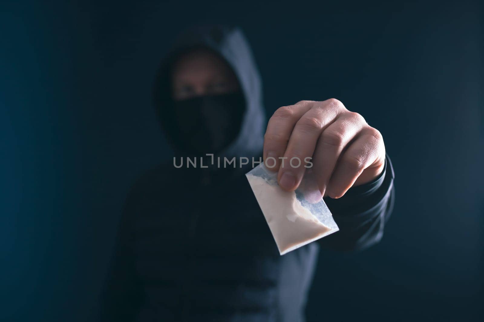 Hand of addict man holding a dose of cocaine or heroine. Concept of drug dealer, drug trafficking, crime, addiction and sale.