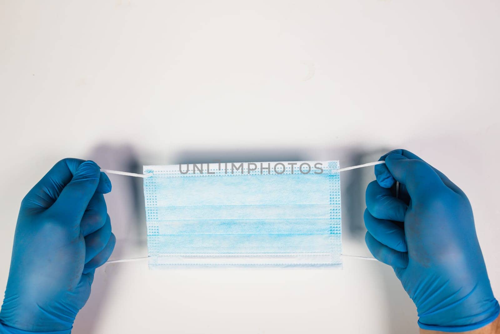 Doctor hand wear blue medical gloves holds antivirus face mask for pandemic diseases. Outbreak, Covid19 concept