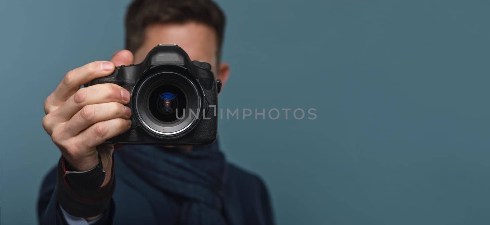 Photographer holding dslr camera on blue modern backround