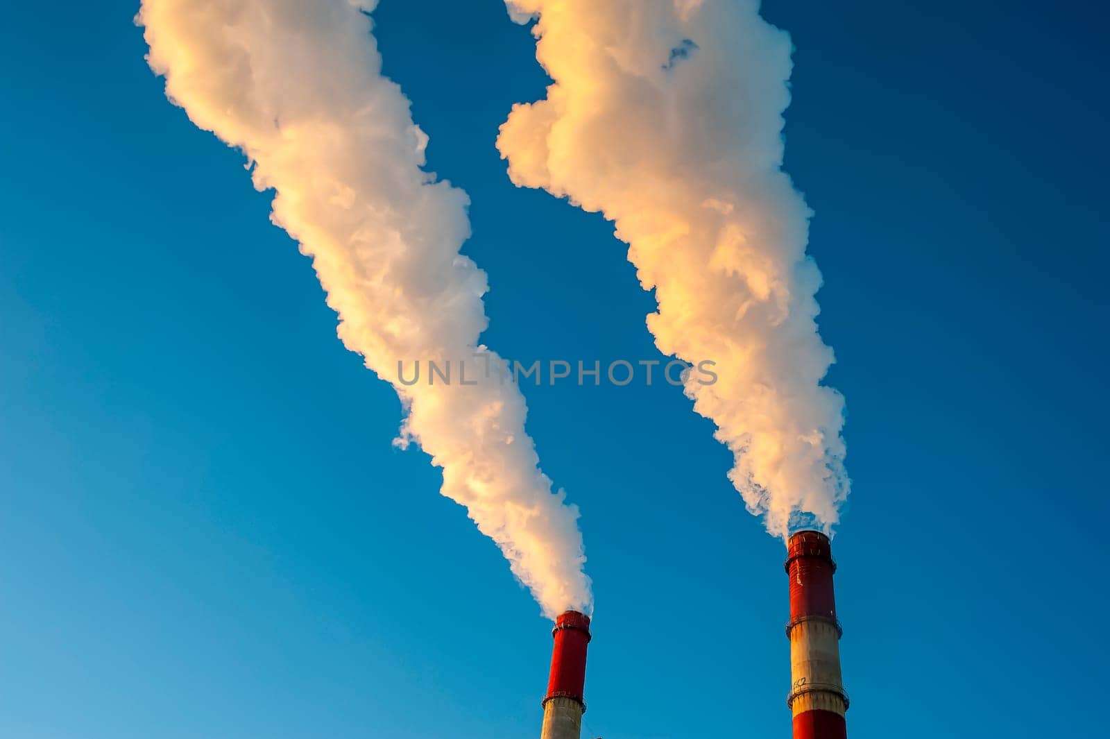white smoke is coming out of the pipes in the blue sky. High quality photo