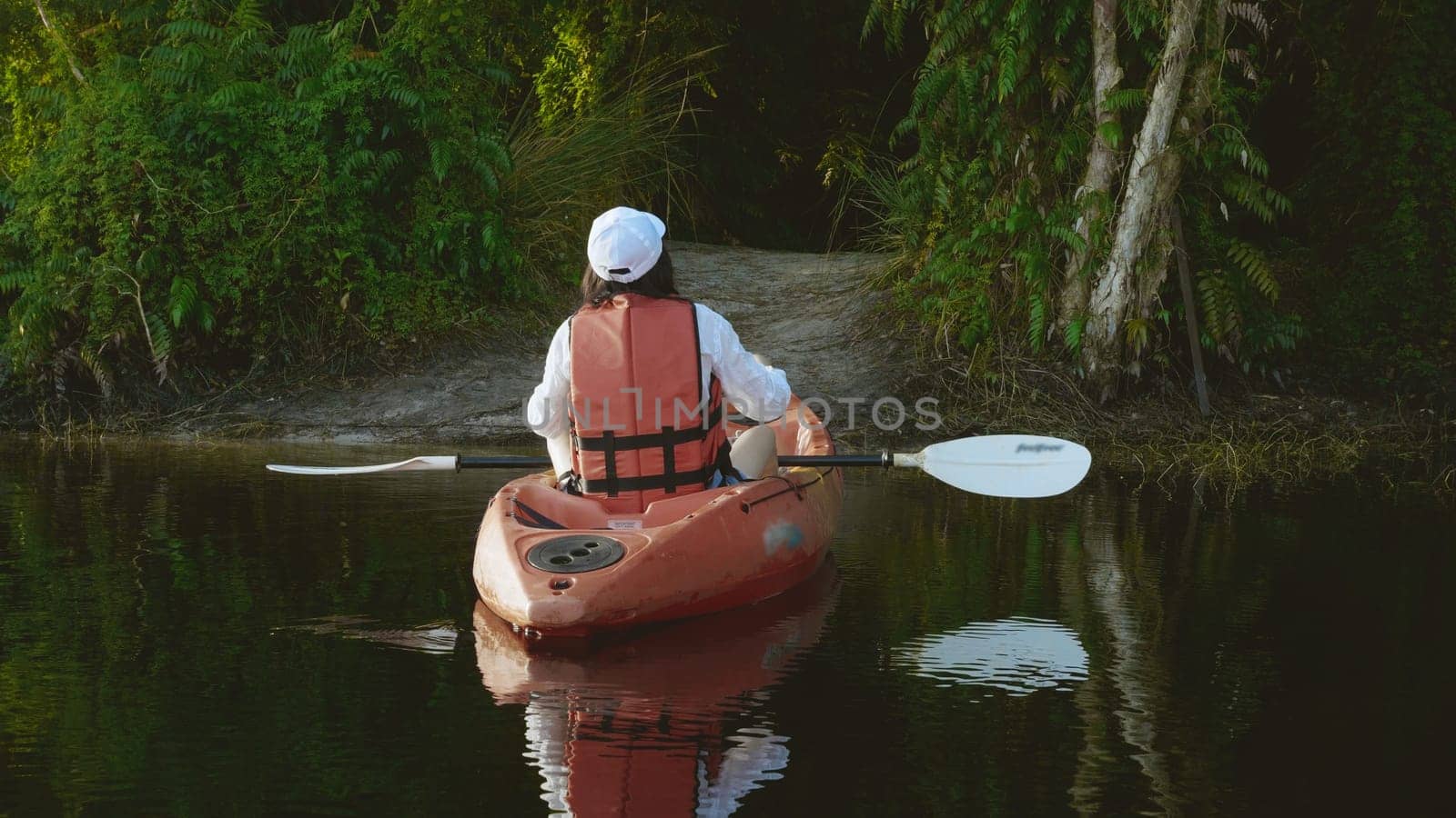 Back young adult woman paddling kayaking canoe on a lake on summer day in rural landscape, adventure travel leisure enjoying concept, lifestyle sport vacation