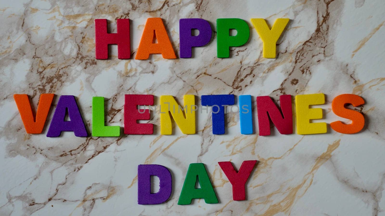 Happy Valentines Day LGBT, colored rainbow text, on marble background close up.