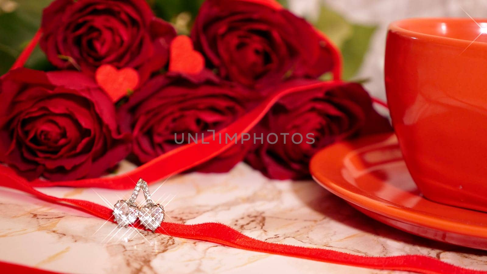 Background Festive Flatlay, composition for Valentine's Day on February 14. Coffee in a red cup, red rose flowers and diamond heart earrings