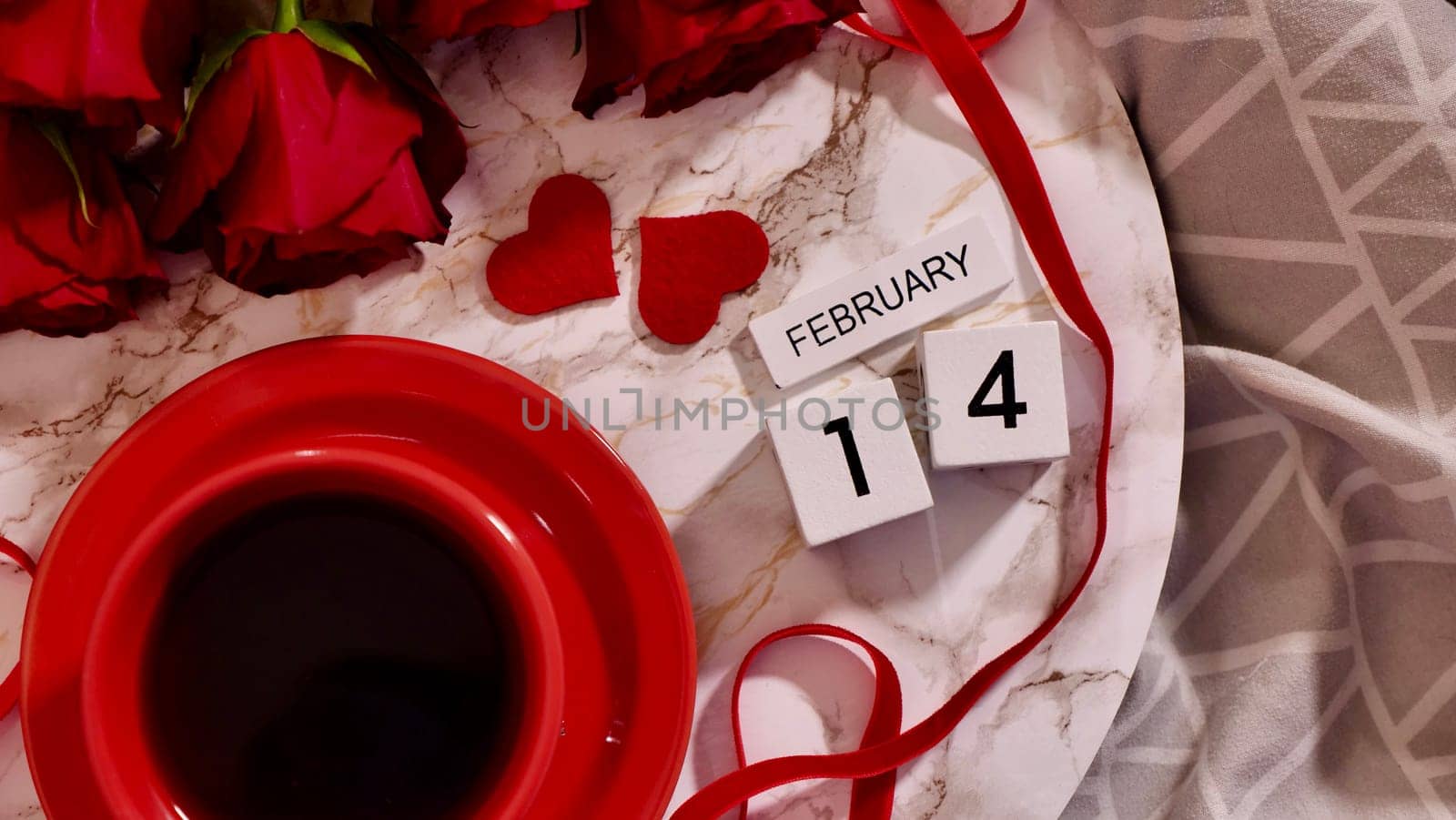 Festive Flatlay, composition for Valentine's Day on February 14. Coffee in a red cup and red rose flowers at home in bed
