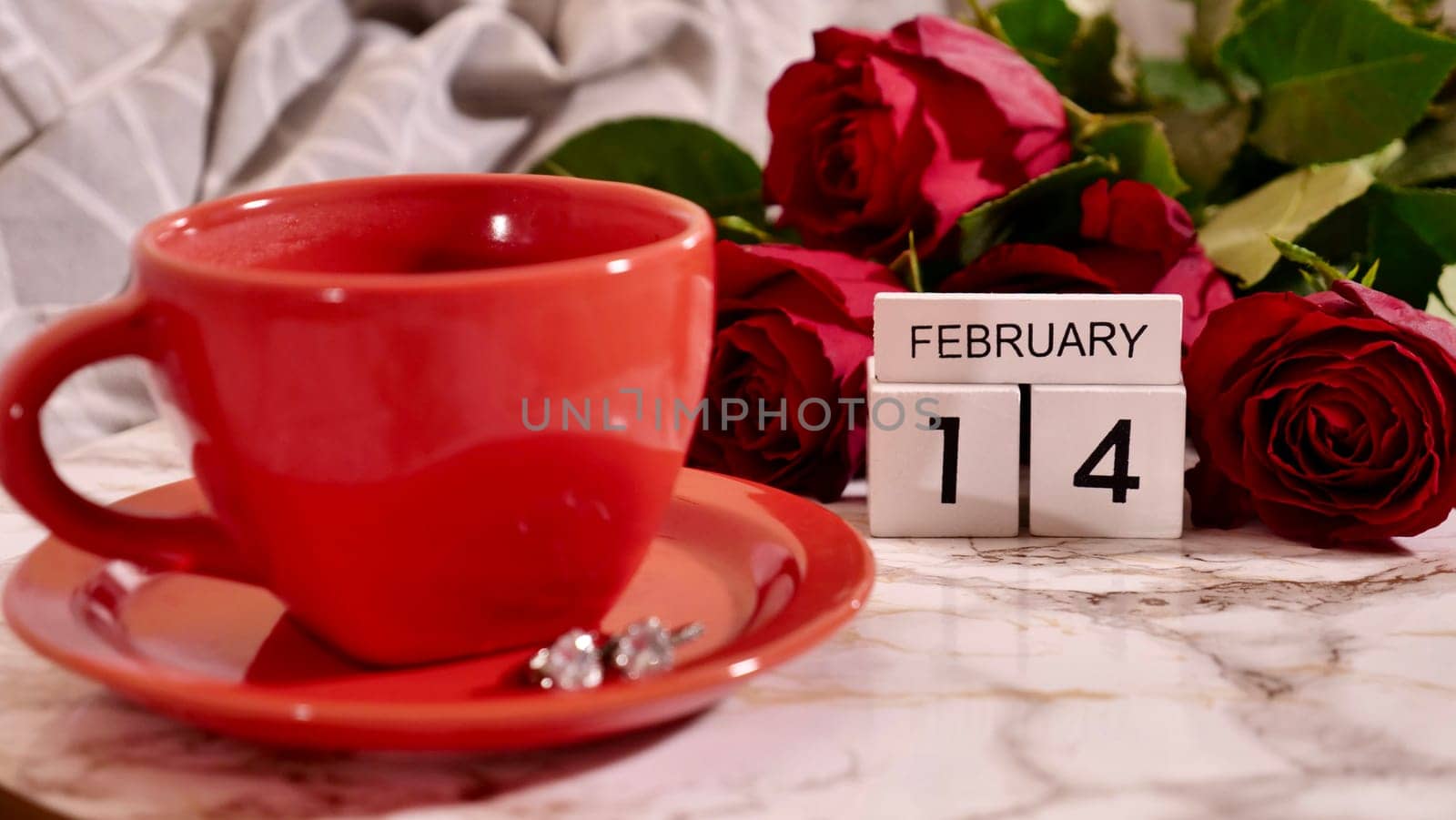 Background Festive Flatlay, composition for Valentine's Day on February 14. Coffee in a red cup, red rose flowers and diamond heart earrings at home in bed