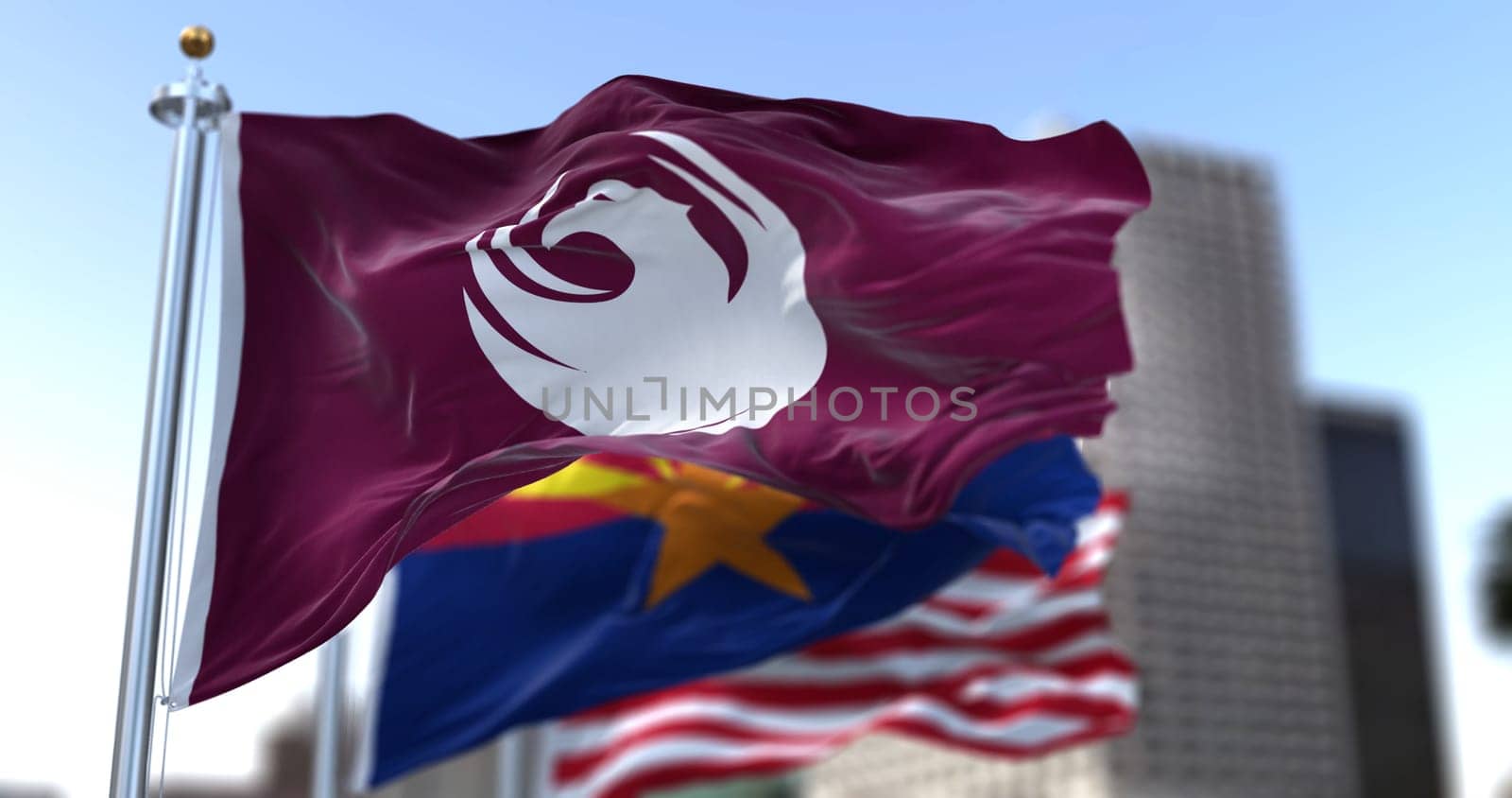 Phoenix city flag waving in the wind with Arizona state and United States national flags blurred in background