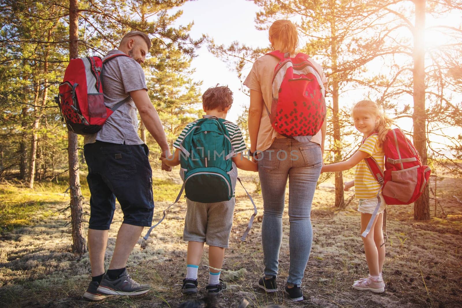 Family with backpacks on the nature near the sea. Concept of the family hiking and joint resting.