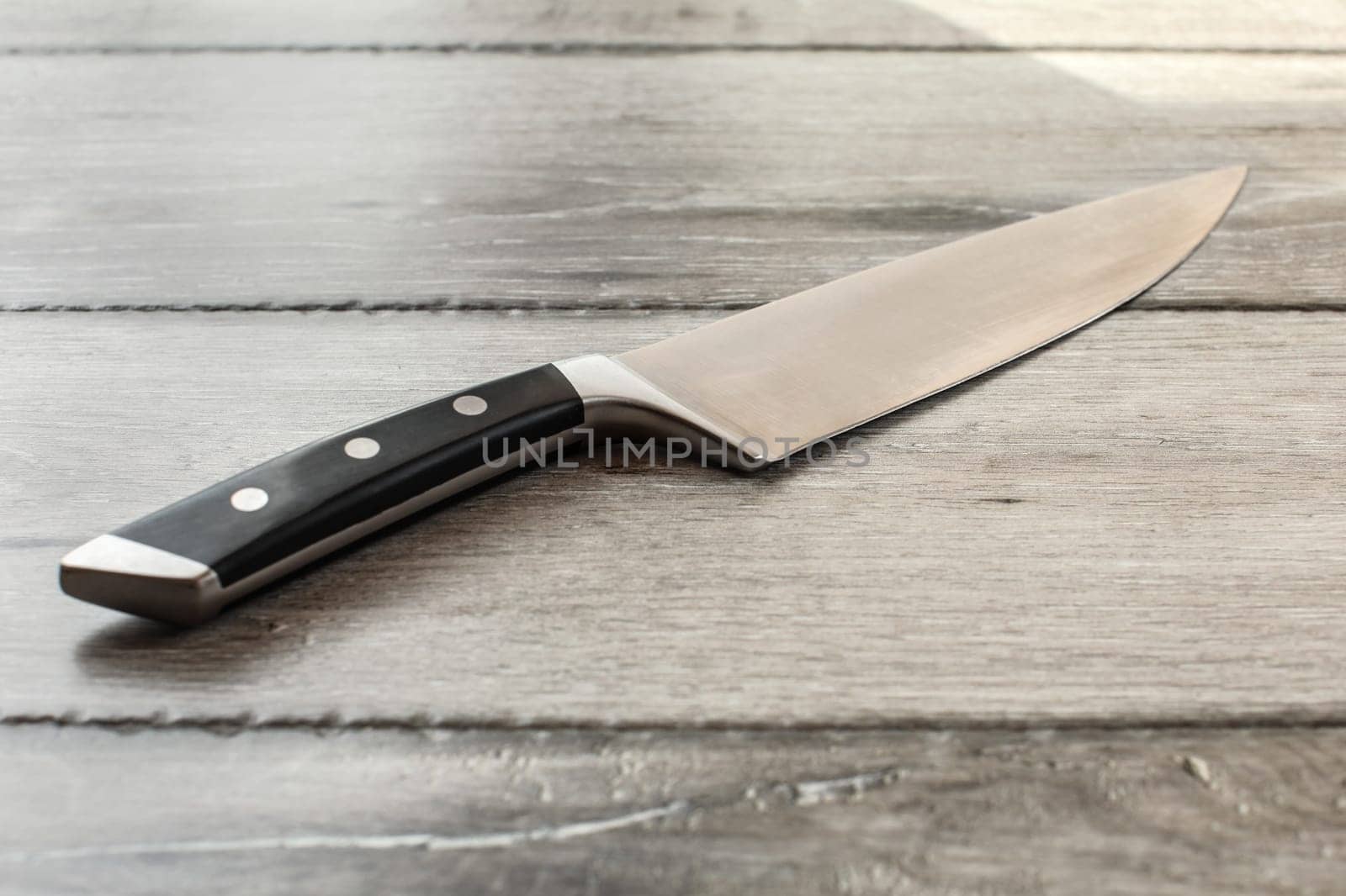 Chef's knife on wooden boards desk.