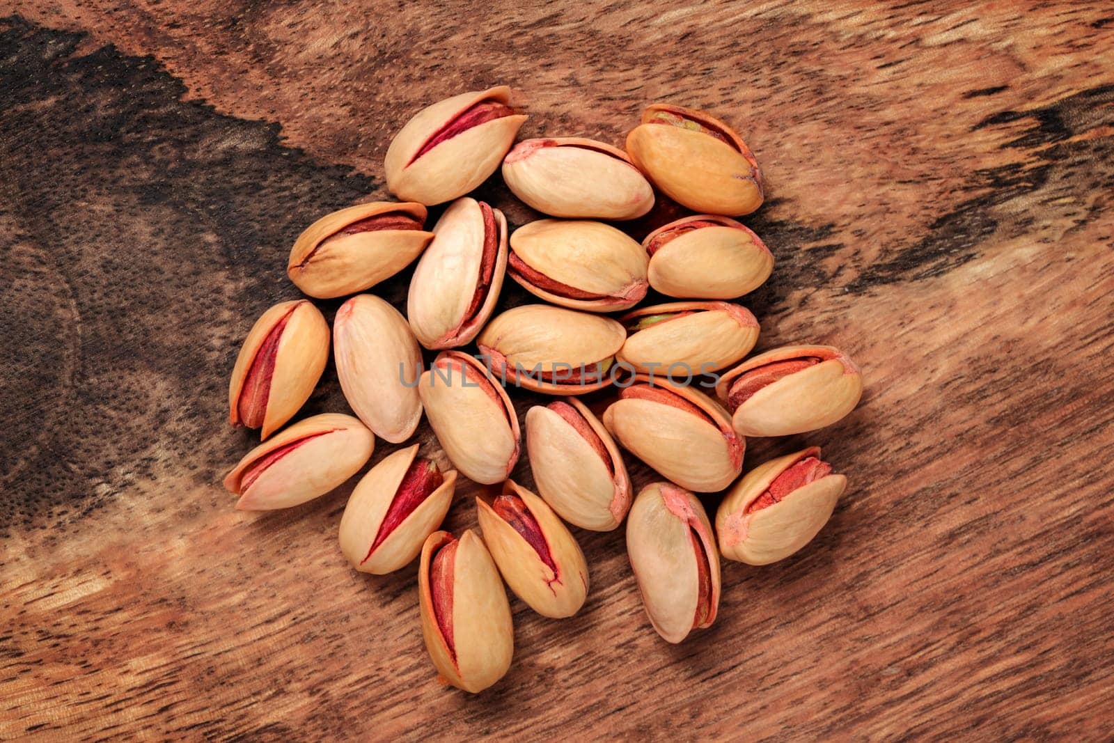 Tabletop view - turkish red roasted pistachios on wooden board.