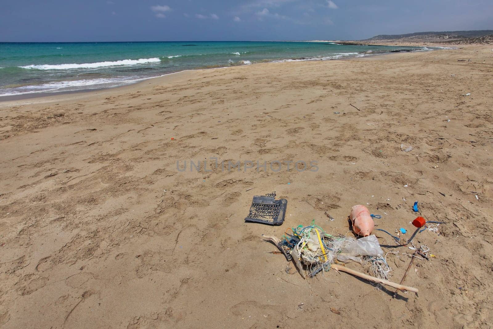 Beautiful empty wild beach in Karpass, Cyprus, with rubbish on the sand. Ocean littering concept.