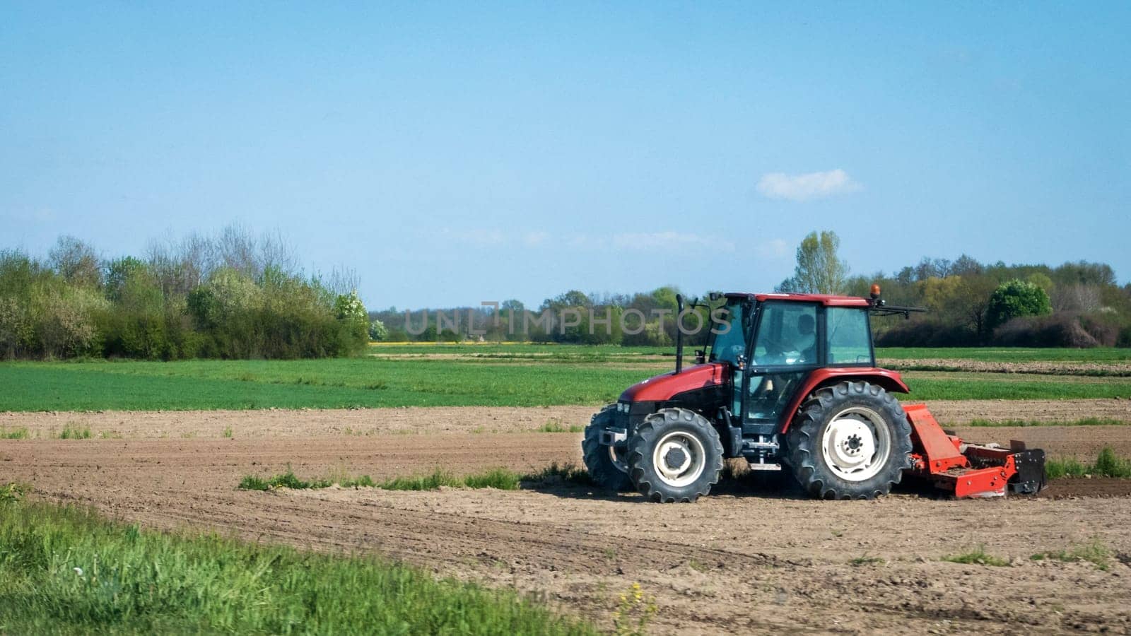 Red tractor ploughing the fields in early spring.