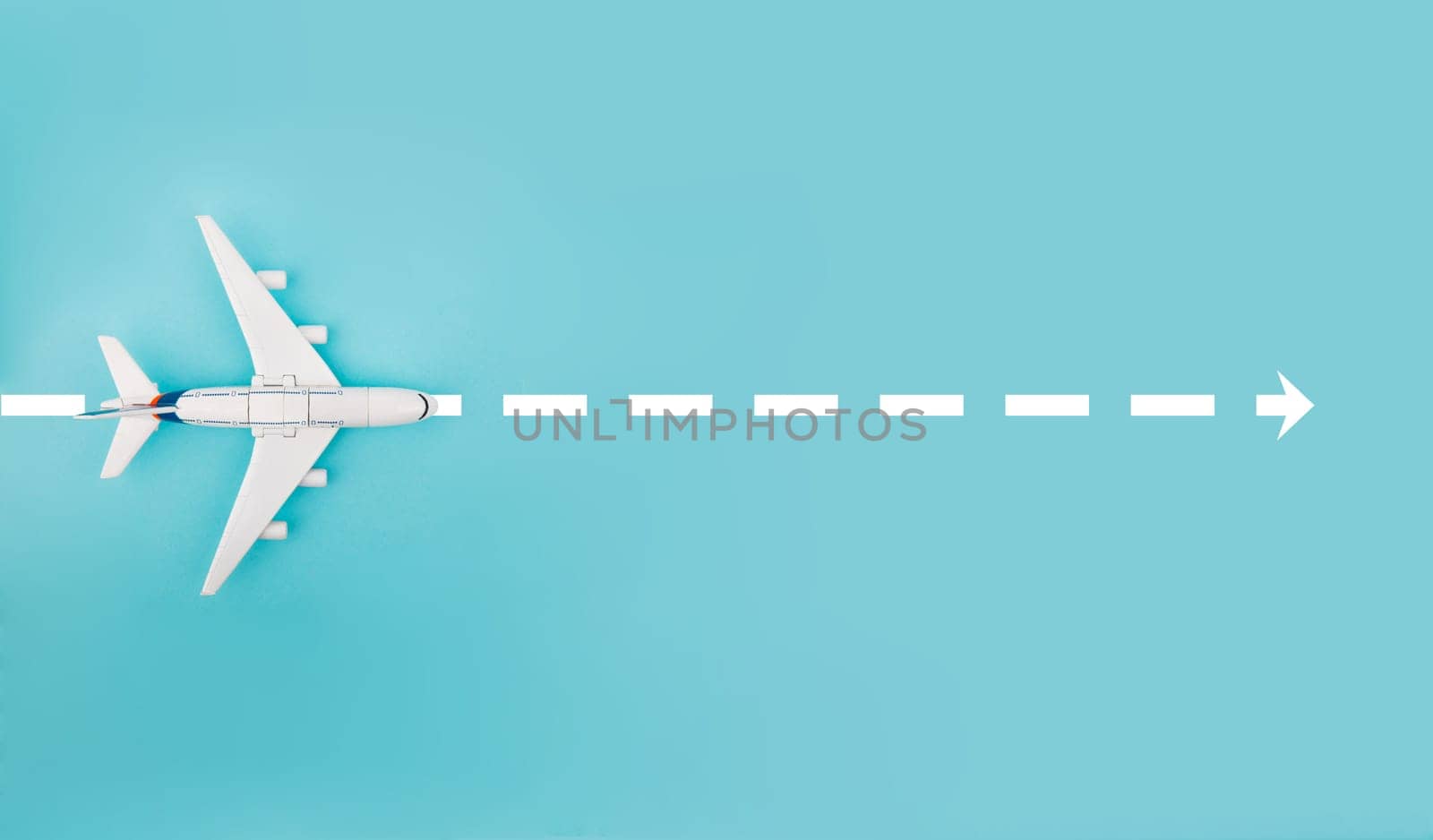 Conceptual with Toy Plane and white arrow isolated over bright blue background