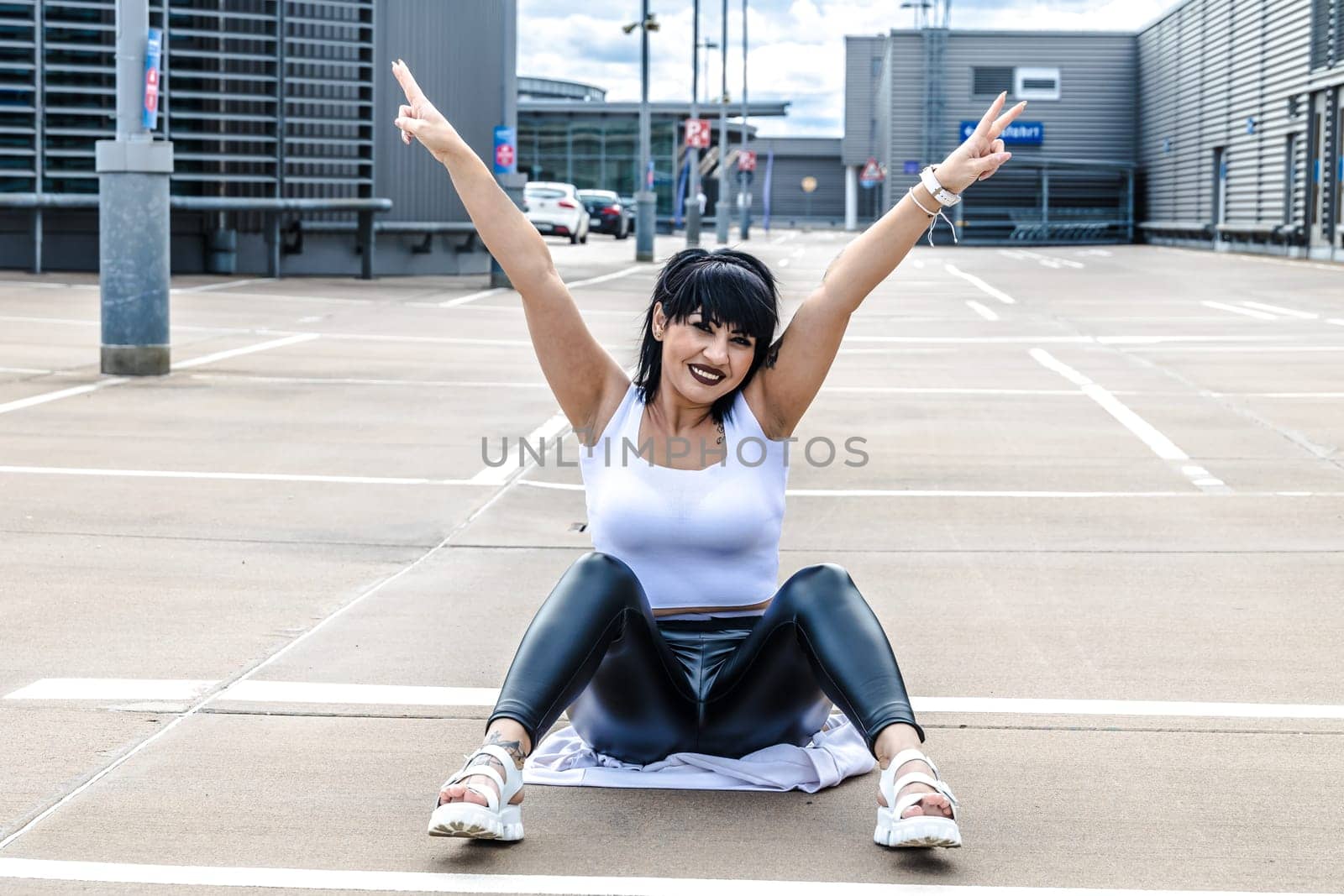 Young woman sitting on the floor and stretching out arms