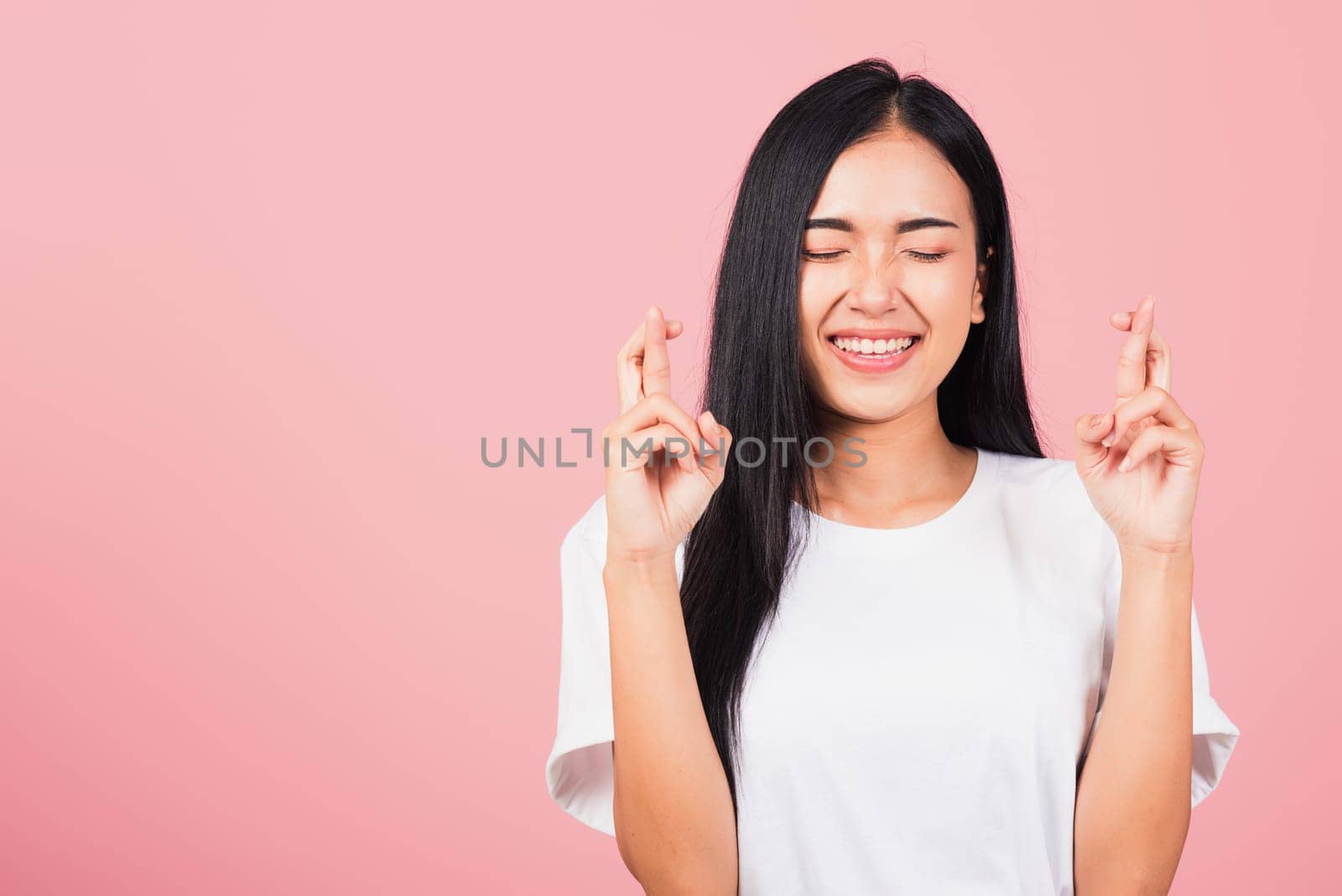 Asian happy portrait beautiful cute young woman smile have superstition her holding fingers crossed for good luck gesture studio shot isolated on pink background, Thai female with copy space