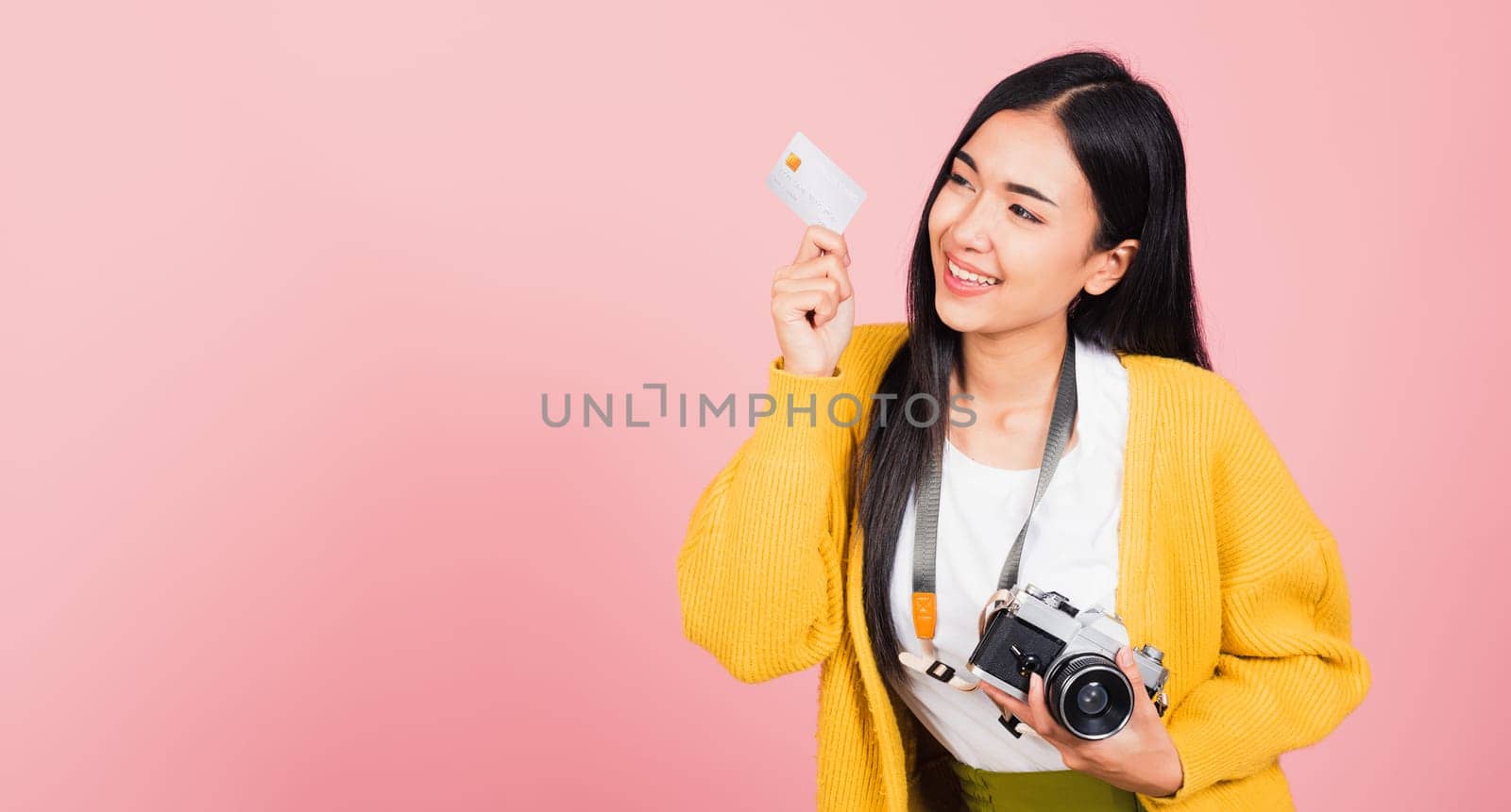 Happy Asian portrait beautiful young woman excited smiling photographer holding credit credit card bank and retro vintage photo camera ready travel isolated on pink background, tourism and vacation