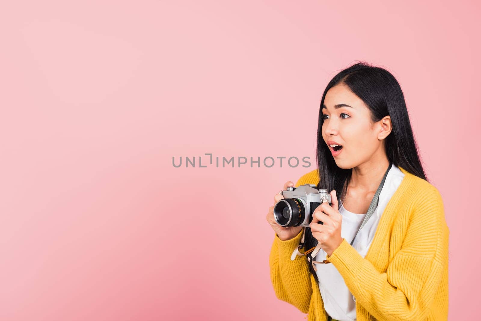 Attractive happy Asian portrait lifestyle beautiful young woman excited smiling photographer holding retro vintage photo camera ready to shoot isolated on pink background, tourism and vacation concept