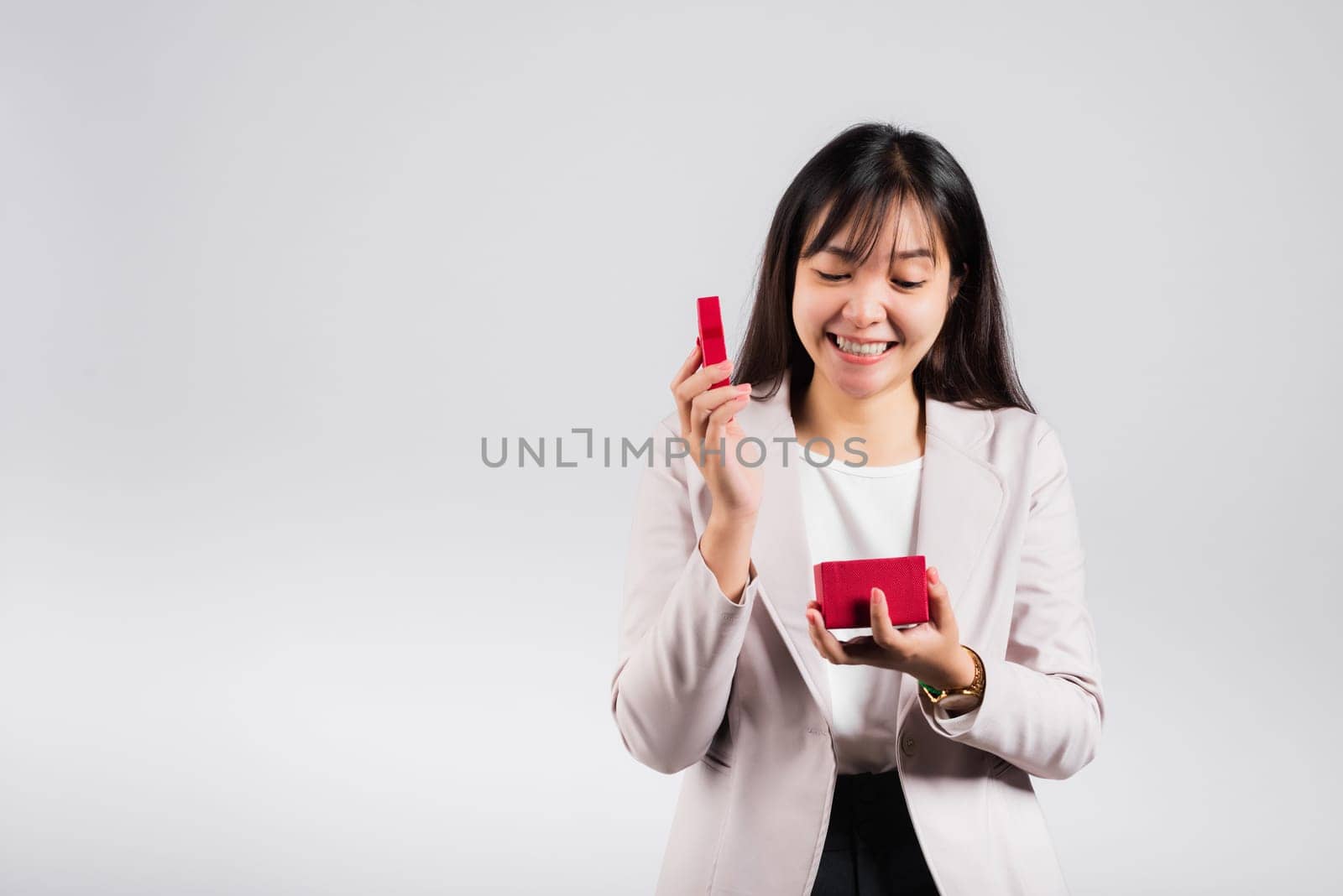 Smiling woman confidence opening a red gift box on palm isolated white background, surprise birthday or Christmas day and valentine, Asian happy portrait beautiful young female studio shot, copy space